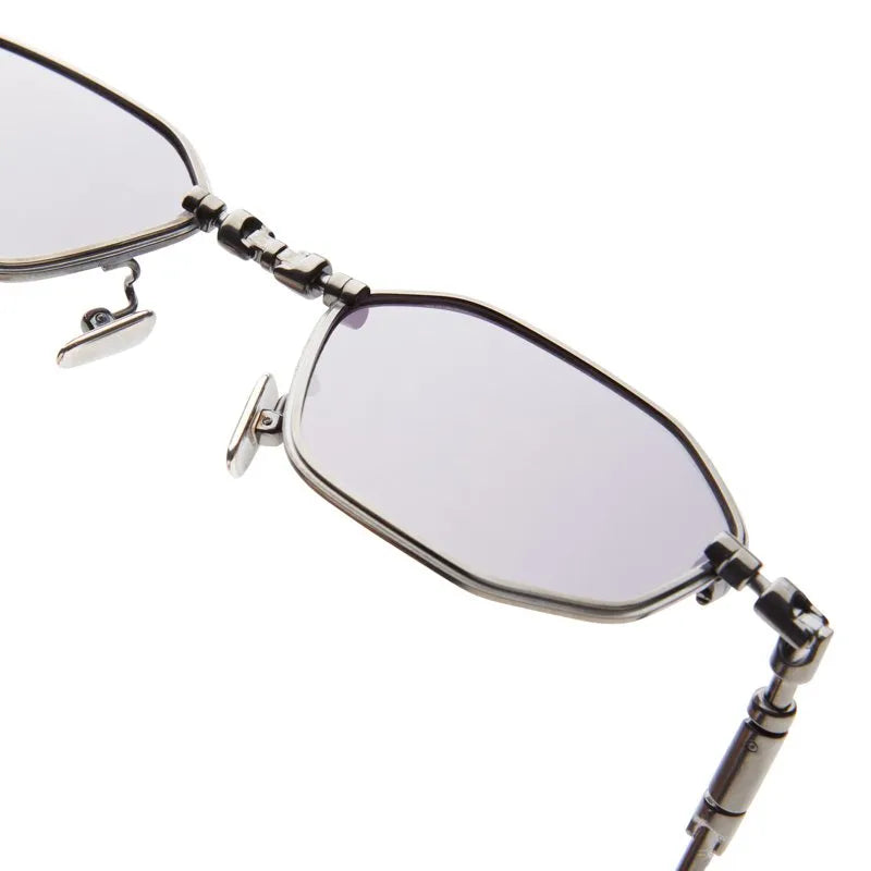 Close-up view of the Kuboraum H66 by Kuboraum, a pair of geometric eyeglasses featuring silver frames, lightly tinted lenses, and adjustable nose pads, handmade in Italy and isolated on a white background.