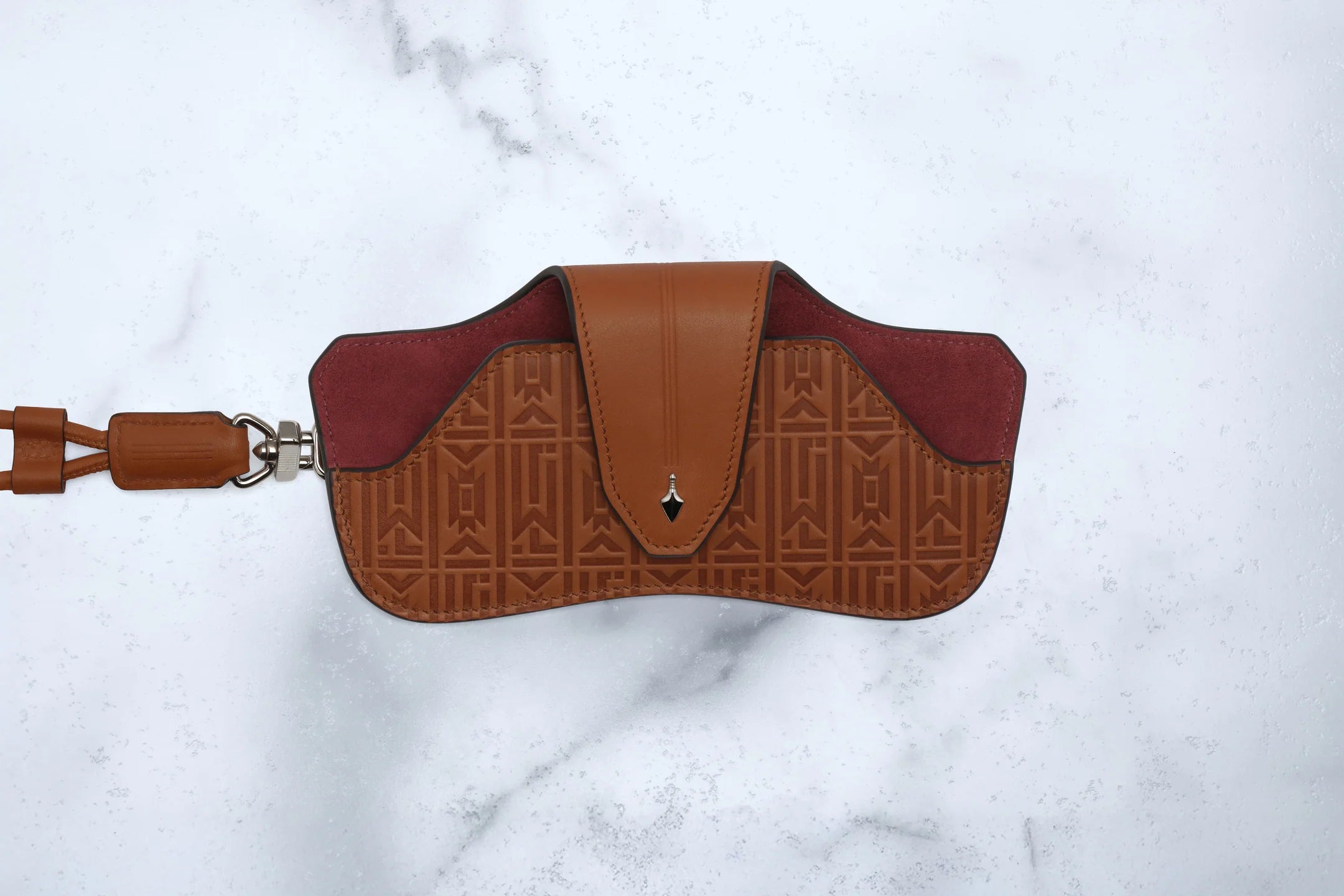 Brown leather saddle pad with embossed pattern on a white marble background
