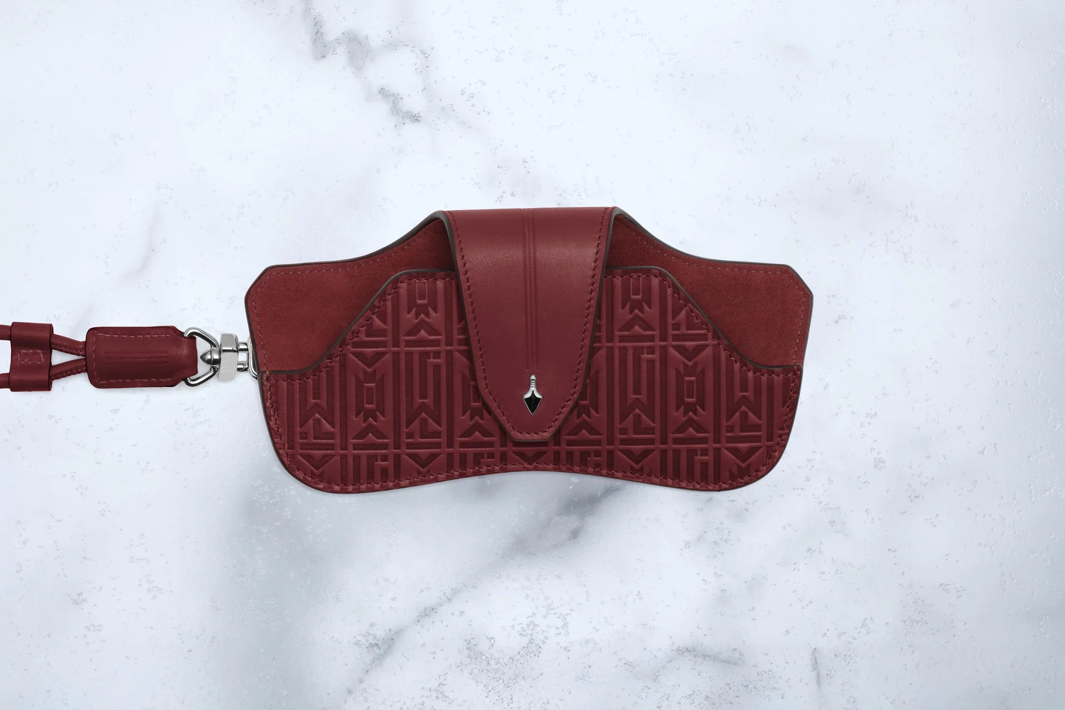 Red handbag with embossed pattern on a white marble background