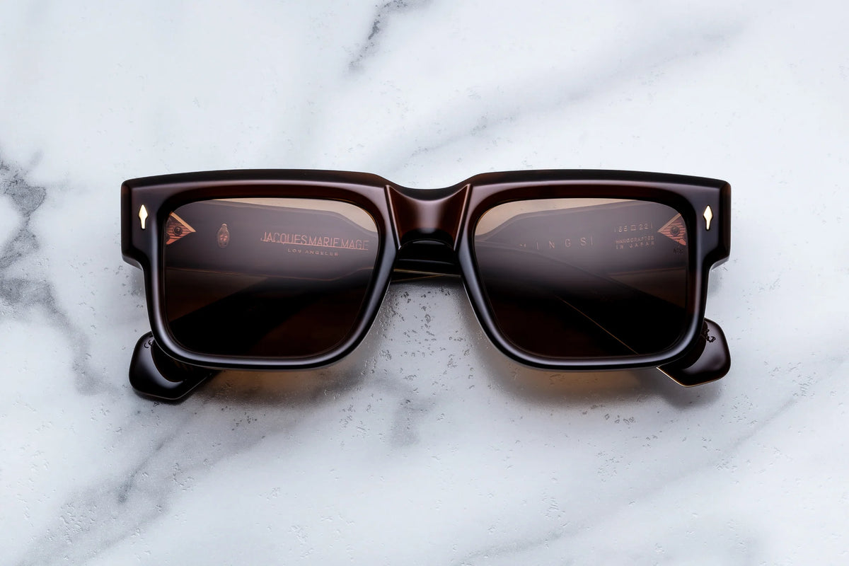 Jacques Marie Mage Hemmings dark brown rectangular sunglasses with gold-tone accents on the frame corners, designed with a sophisticated 60s-inspired aesthetic.