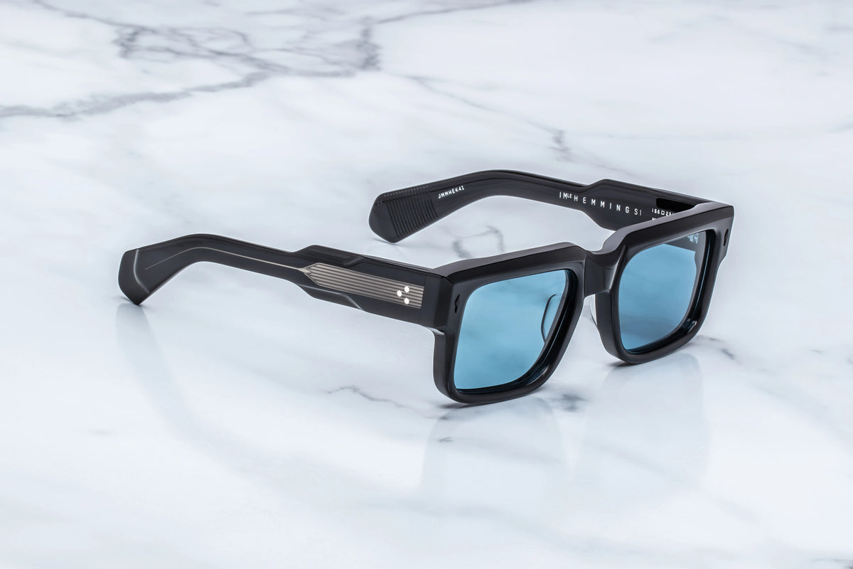 Jacques Marie Mage Hemmings black rectangular sunglasses with light blue lenses and metallic temple accents, capturing a sophisticated eyewear aesthetic.