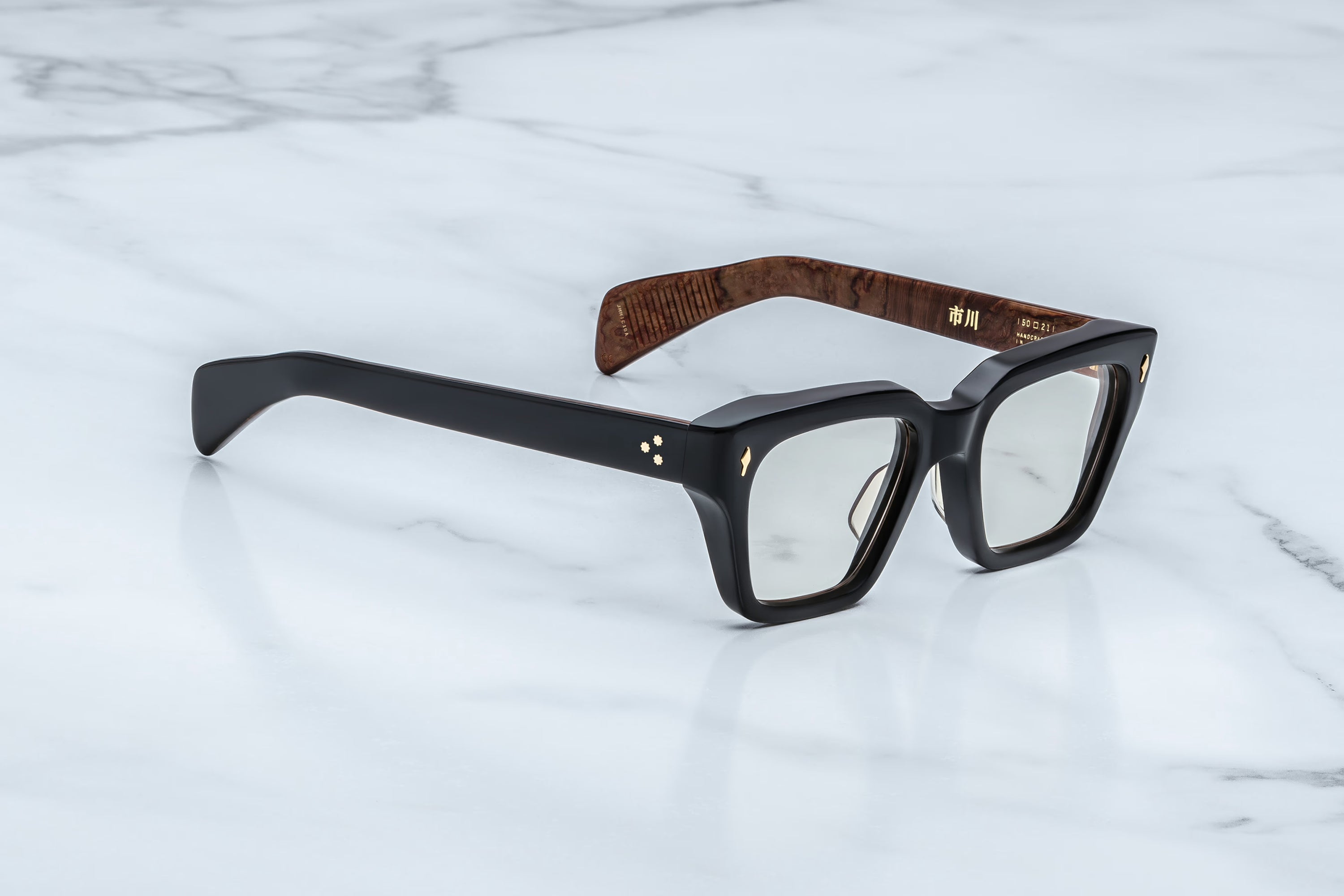 Black eyeglasses with wooden temple tips on a white marble surface