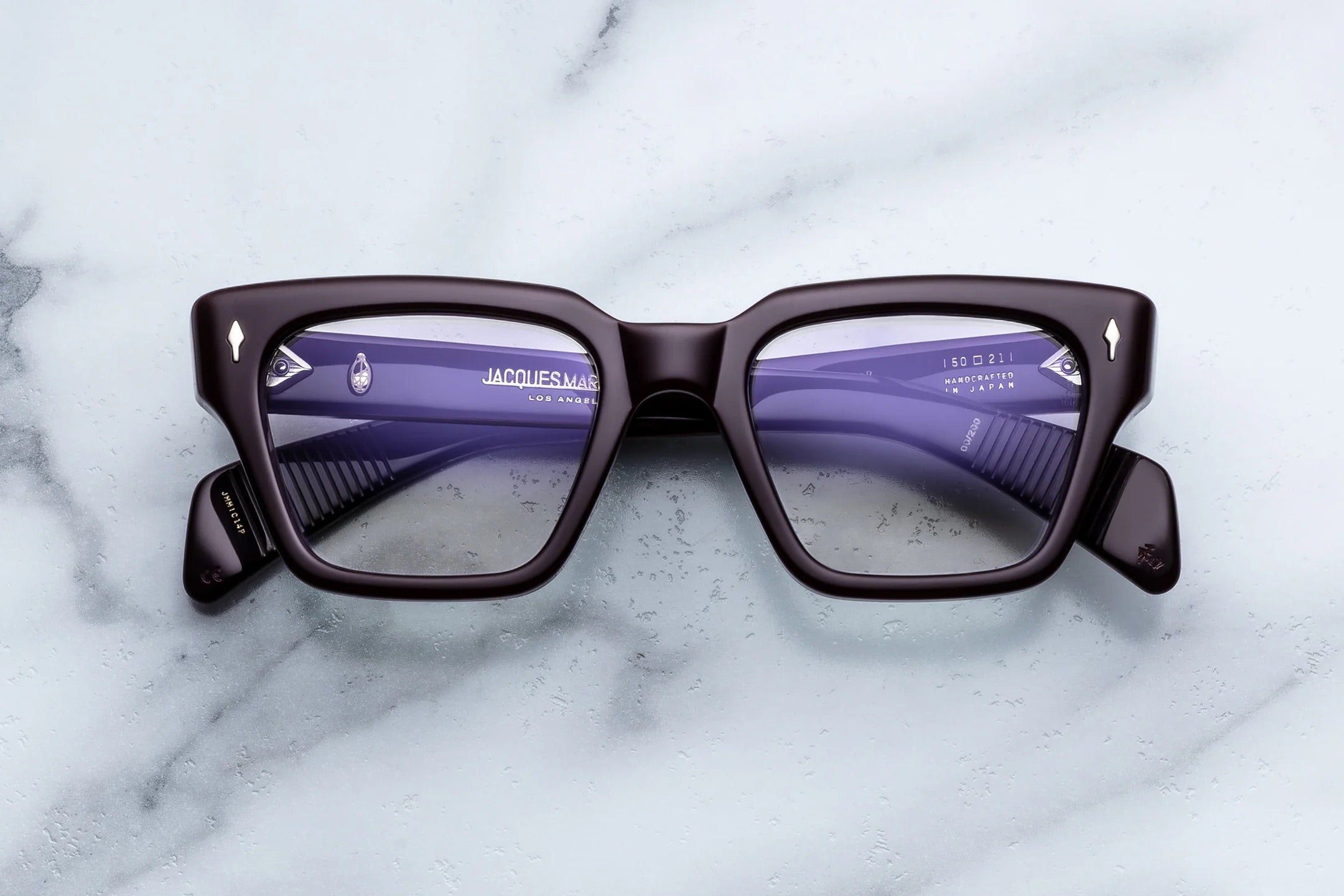 Pair of glasses with purple lenses on a marble surface