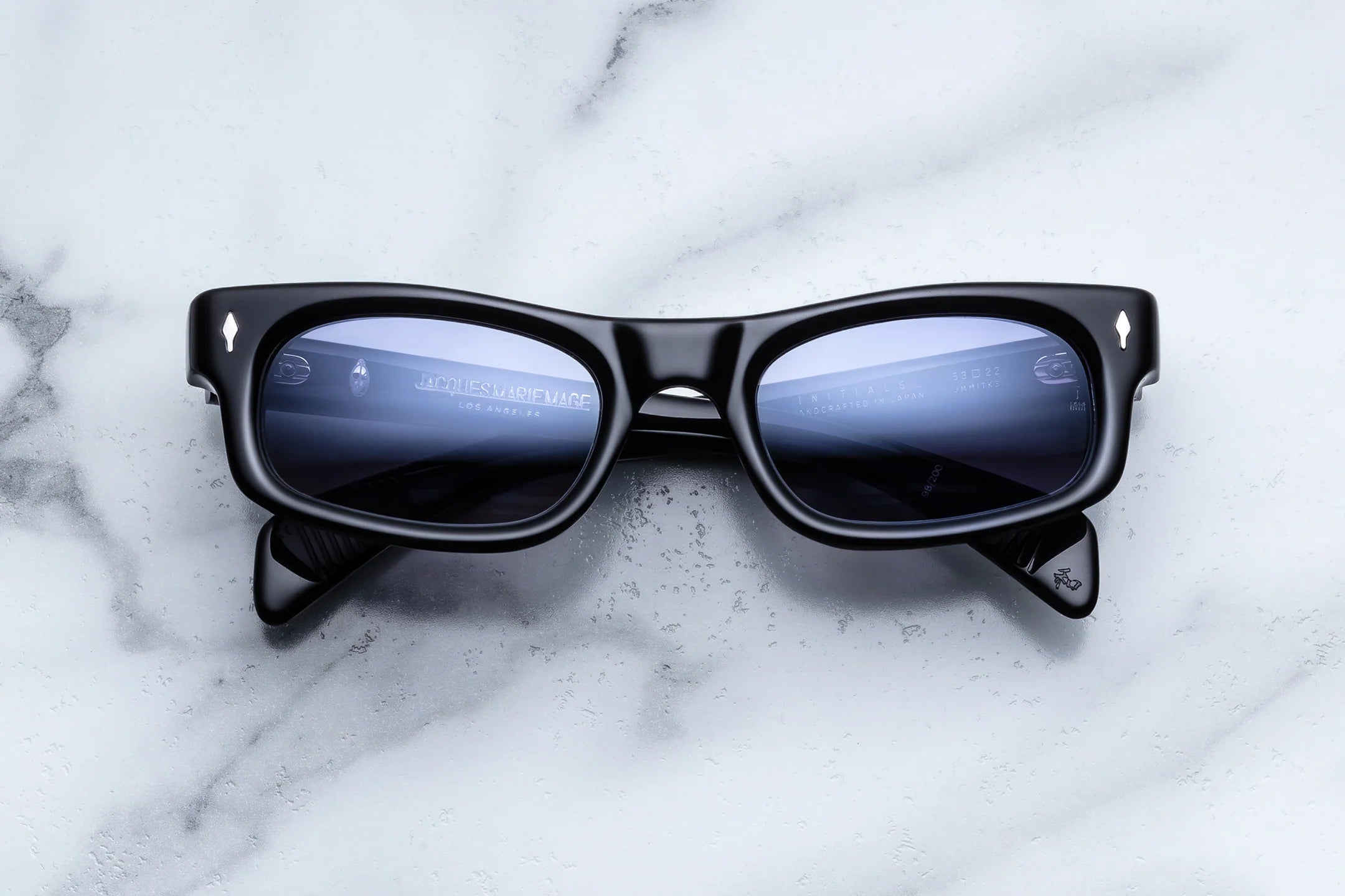 Black sunglasses with reflective lenses on a marble surface