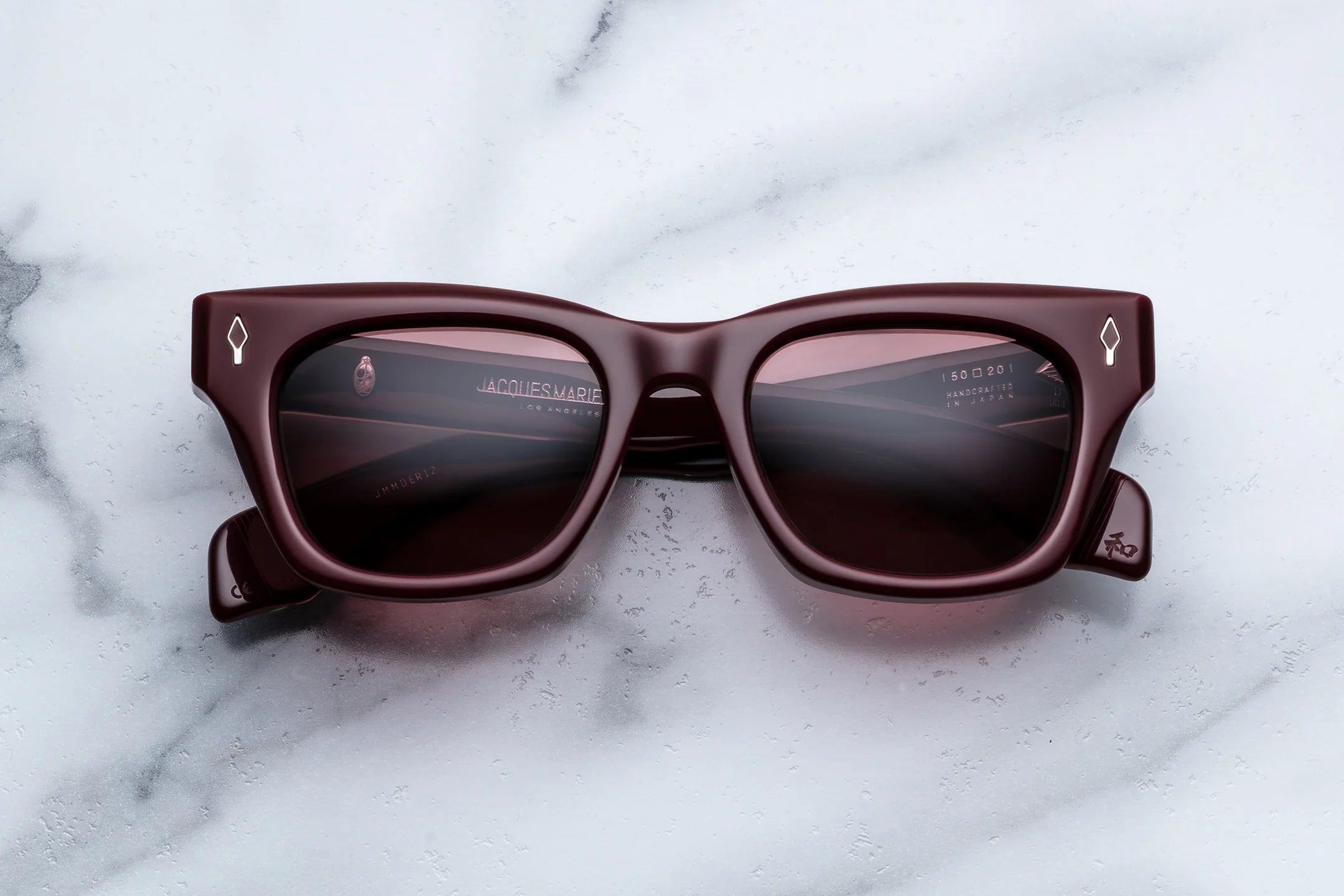 Brown Red wayfarer sunglasses with dark lenses on a marble surface