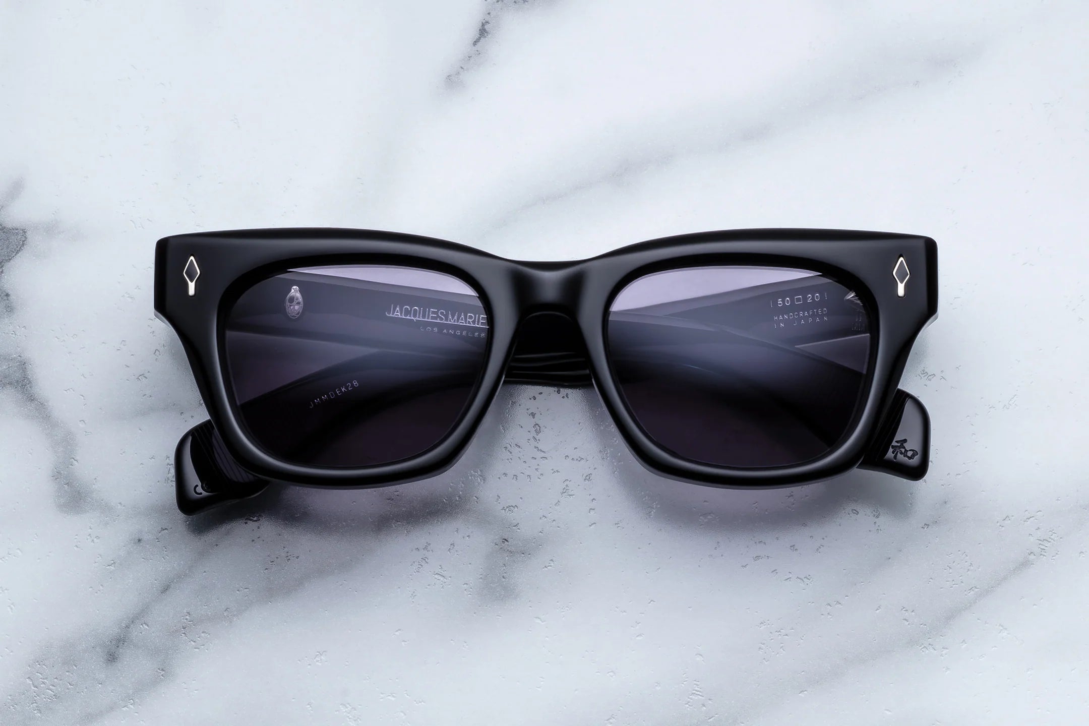 Classic Wayfarer Black sunglasses with a brand logo on a white marble surface