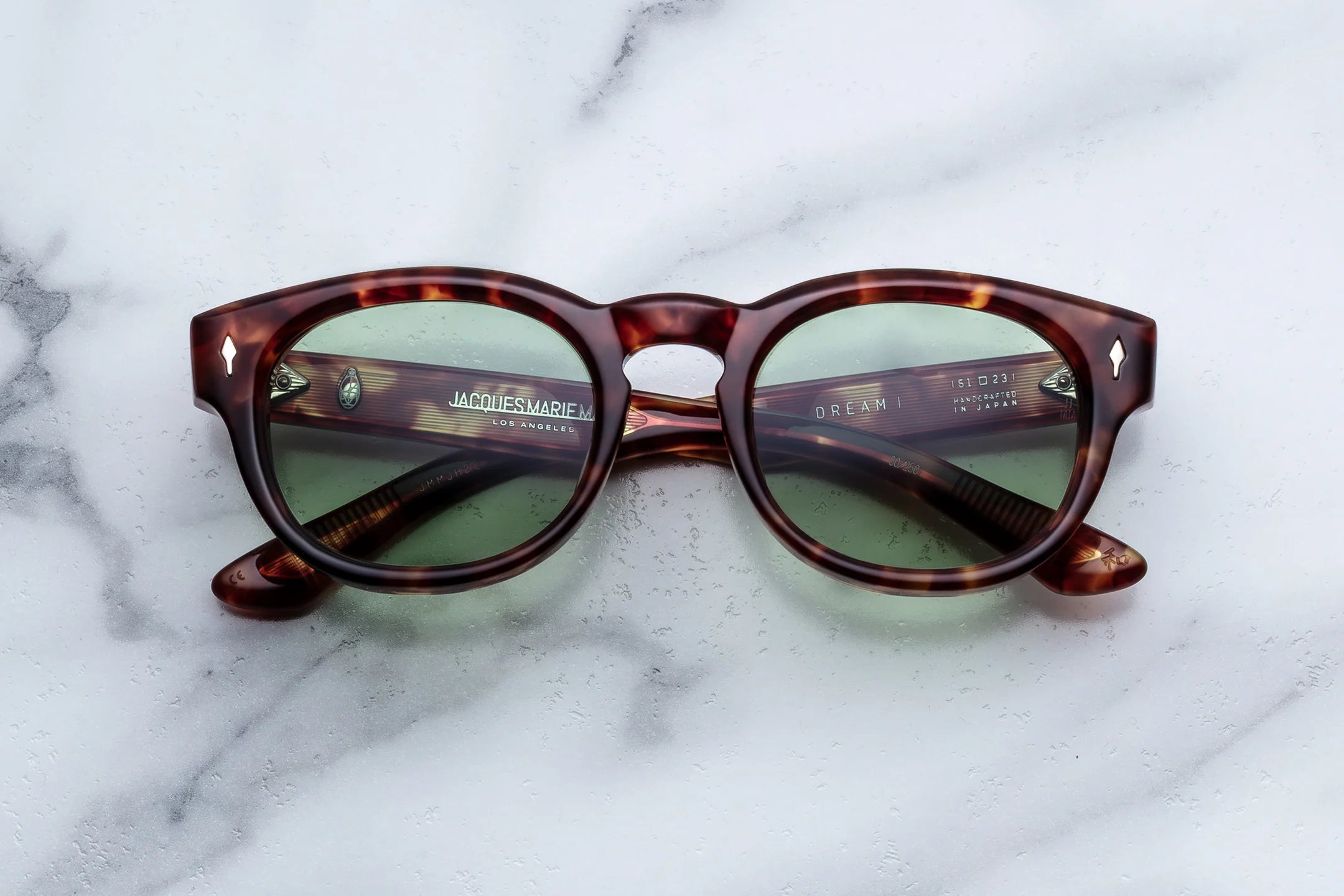 Thick Acetate Tortoiseshell sunglasses with green lenses on a marble surface