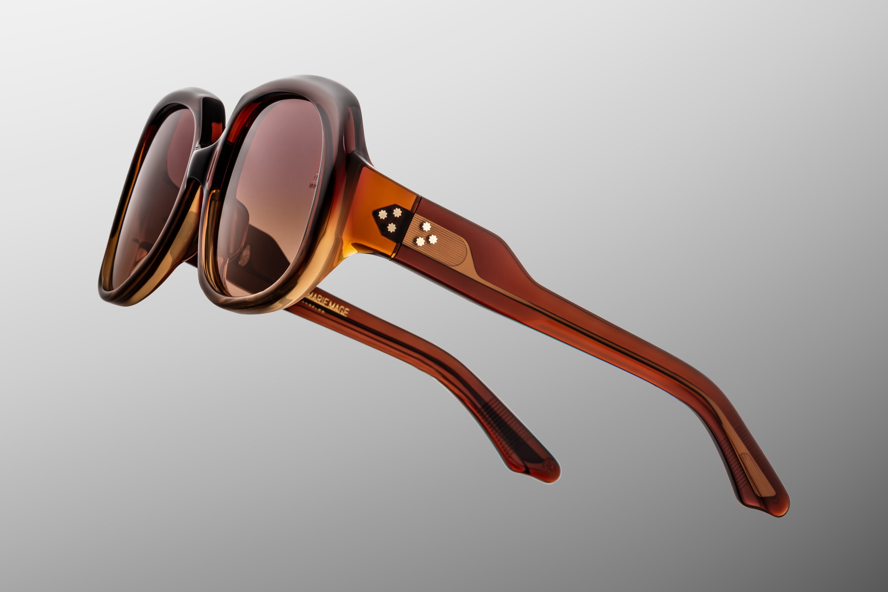 Brown sunglasses with a visible brand logo on a gray background
