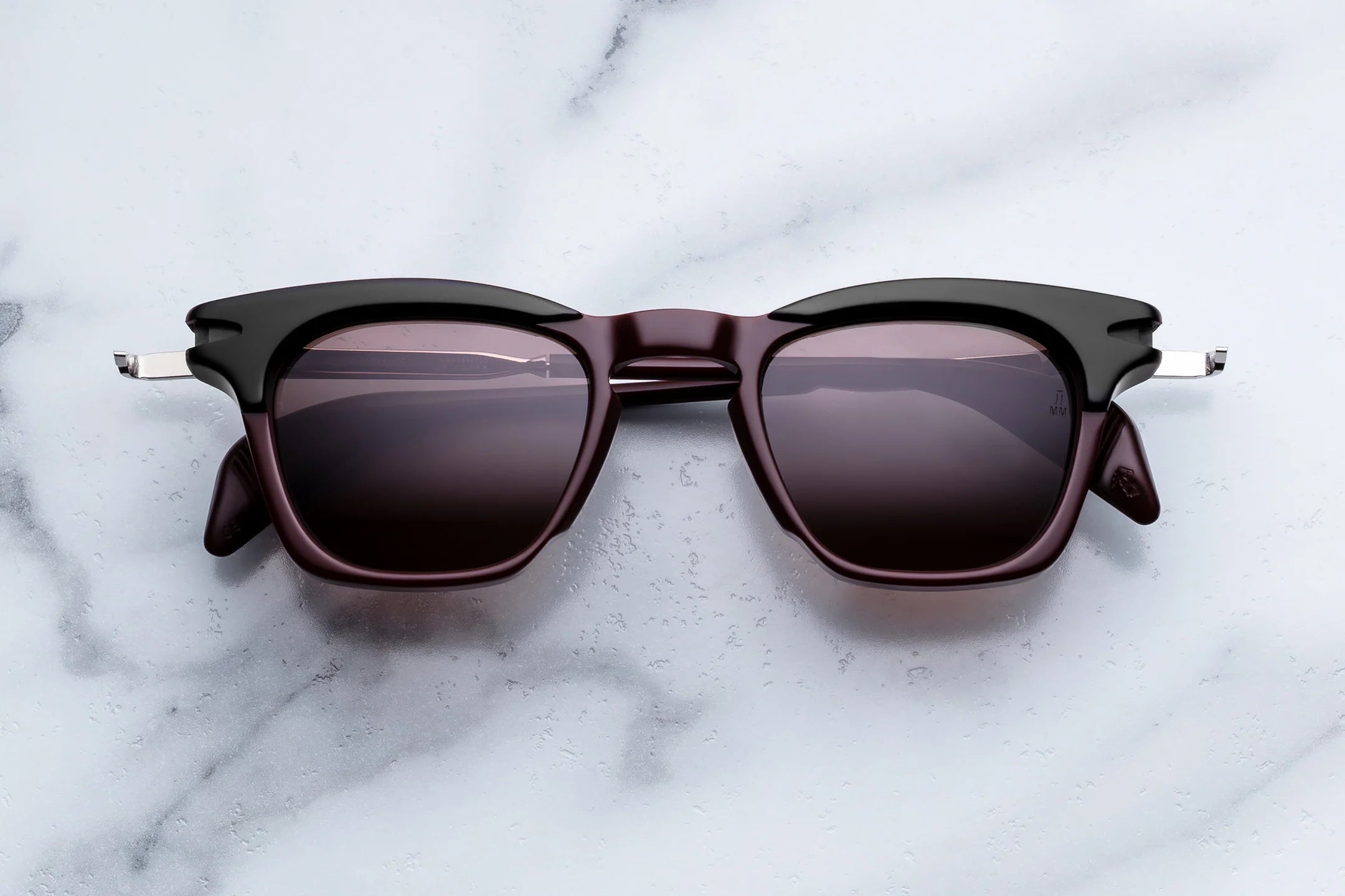 Sunglasses with black frame and dark lenses on a marble surface