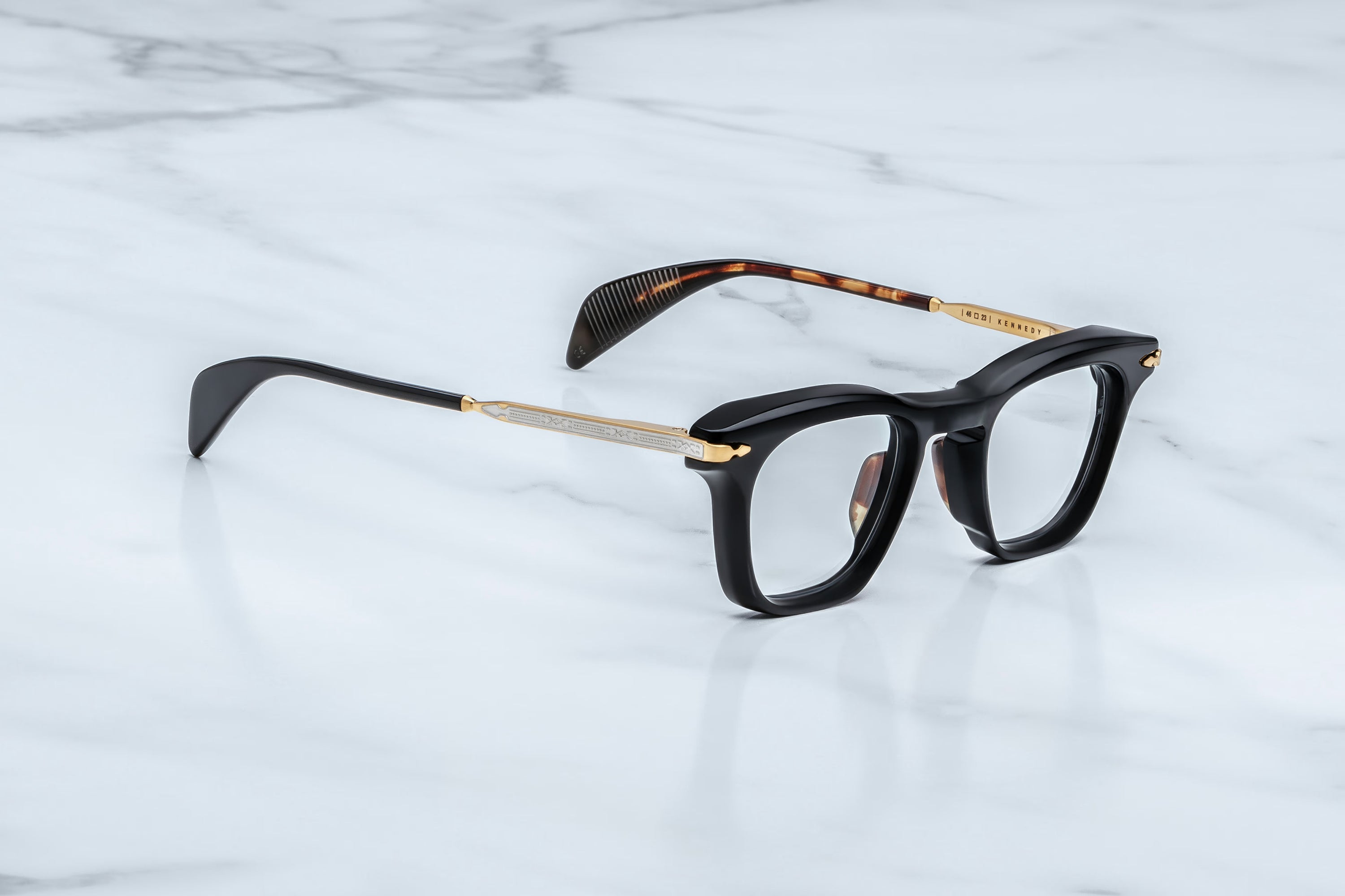 Black and gold eyeglasses on a light gray marble background
