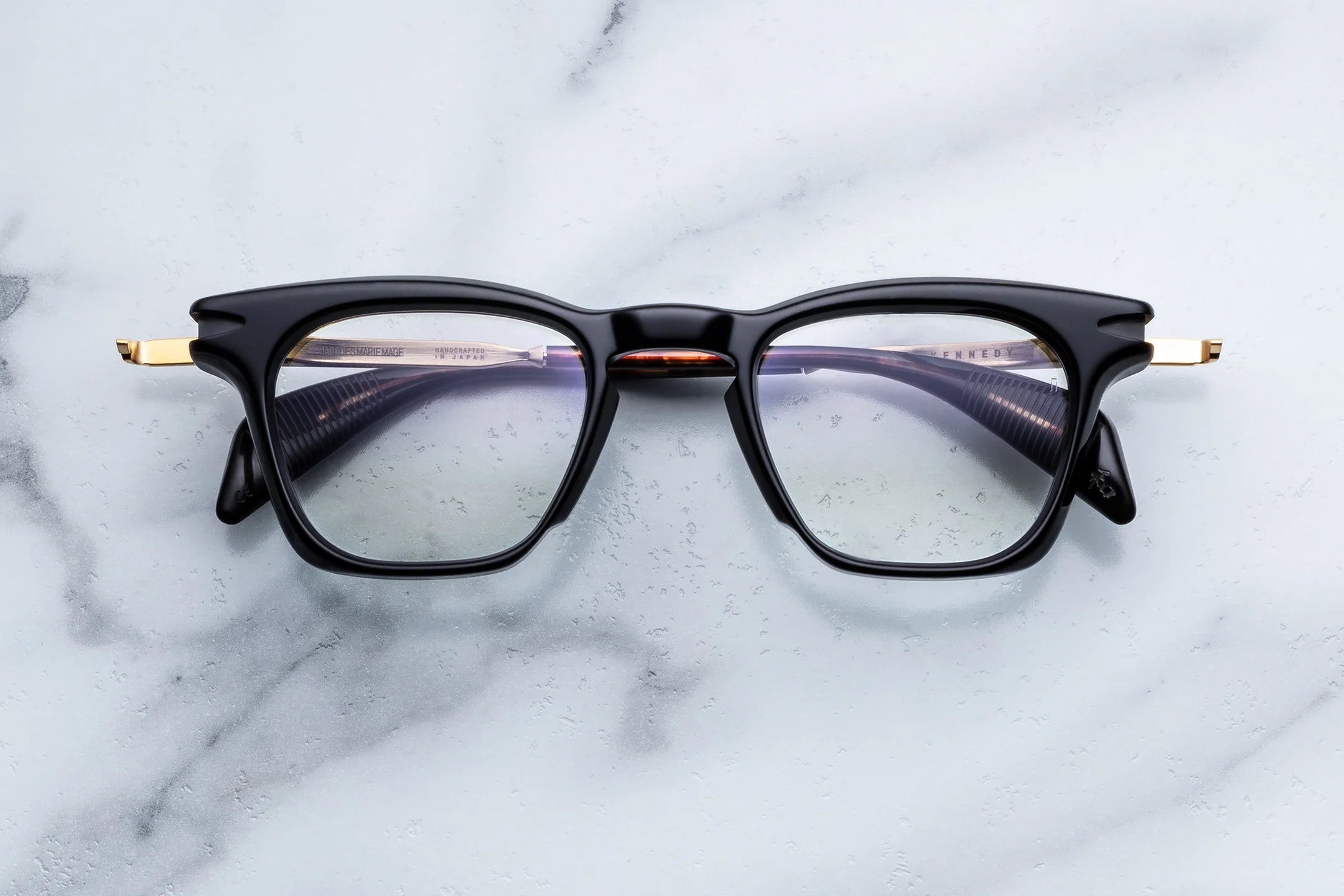 Black cat-eye glasses with gold accents on a marble surface