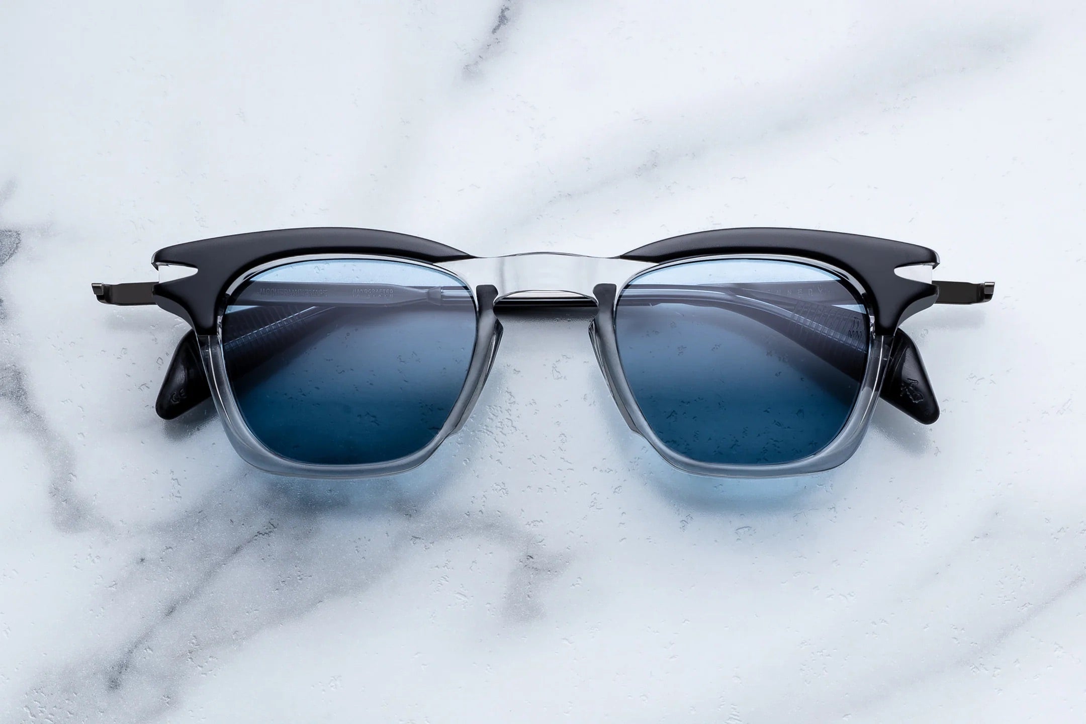 Sunglasses with black frames and blue lenses on a marble surface