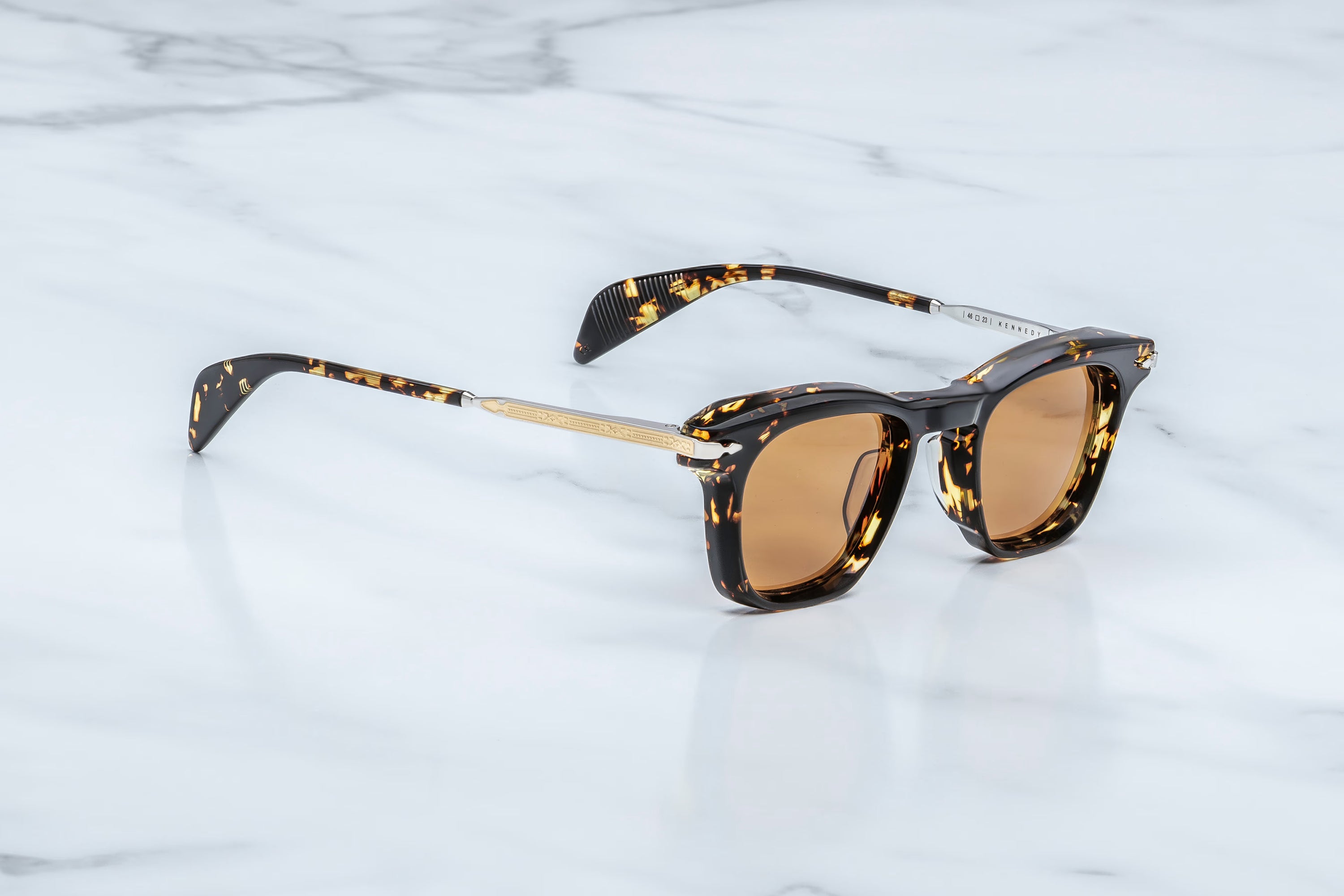 Sunglasses with tortoiseshell frame and brown lenses on a light marble background