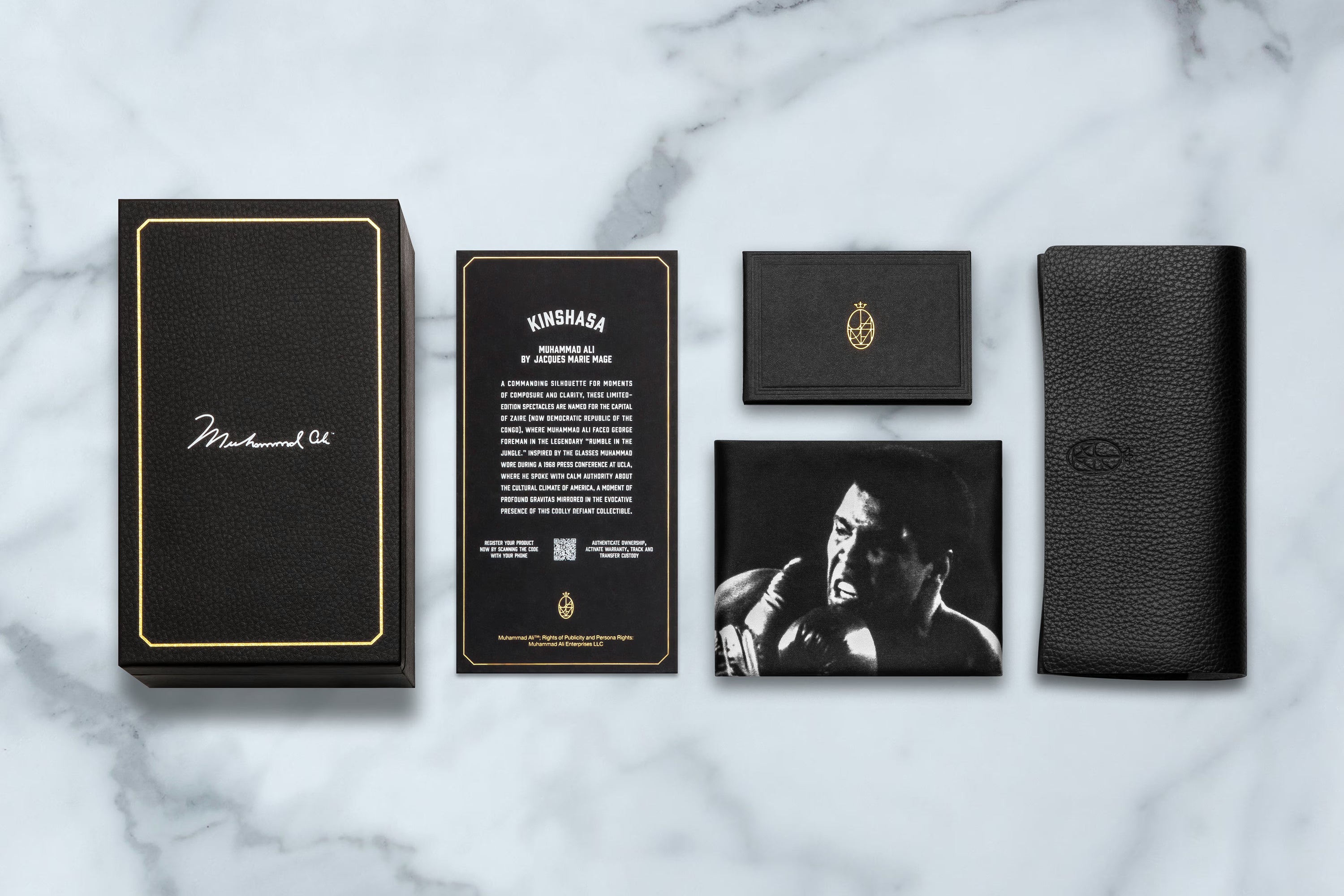 Collection of black leather products with gold accents on a marble surface
