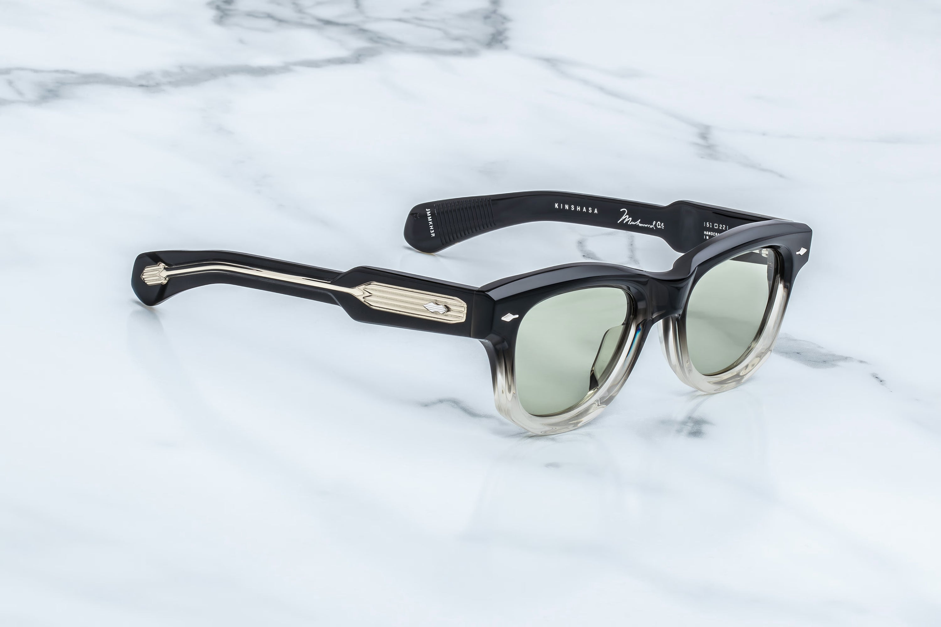 Sunglasses with a black frame and reflective lenses on a light blue marble background