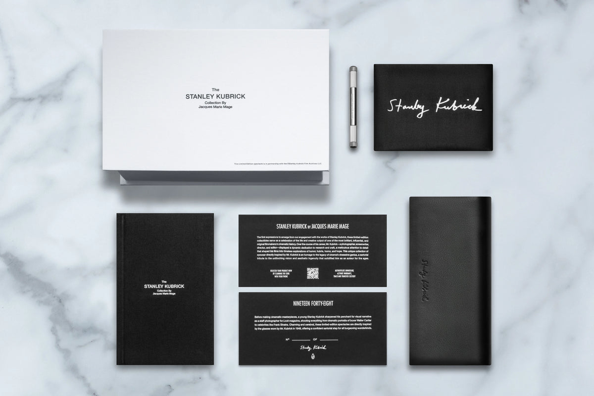 A collection of Stanley Kubrick by JMM: 1948 limited-edition eyewear accessories including a branded box, a silver pen, a black leather case, a notebook, and two informational cards highlighting this cinematic tribute.