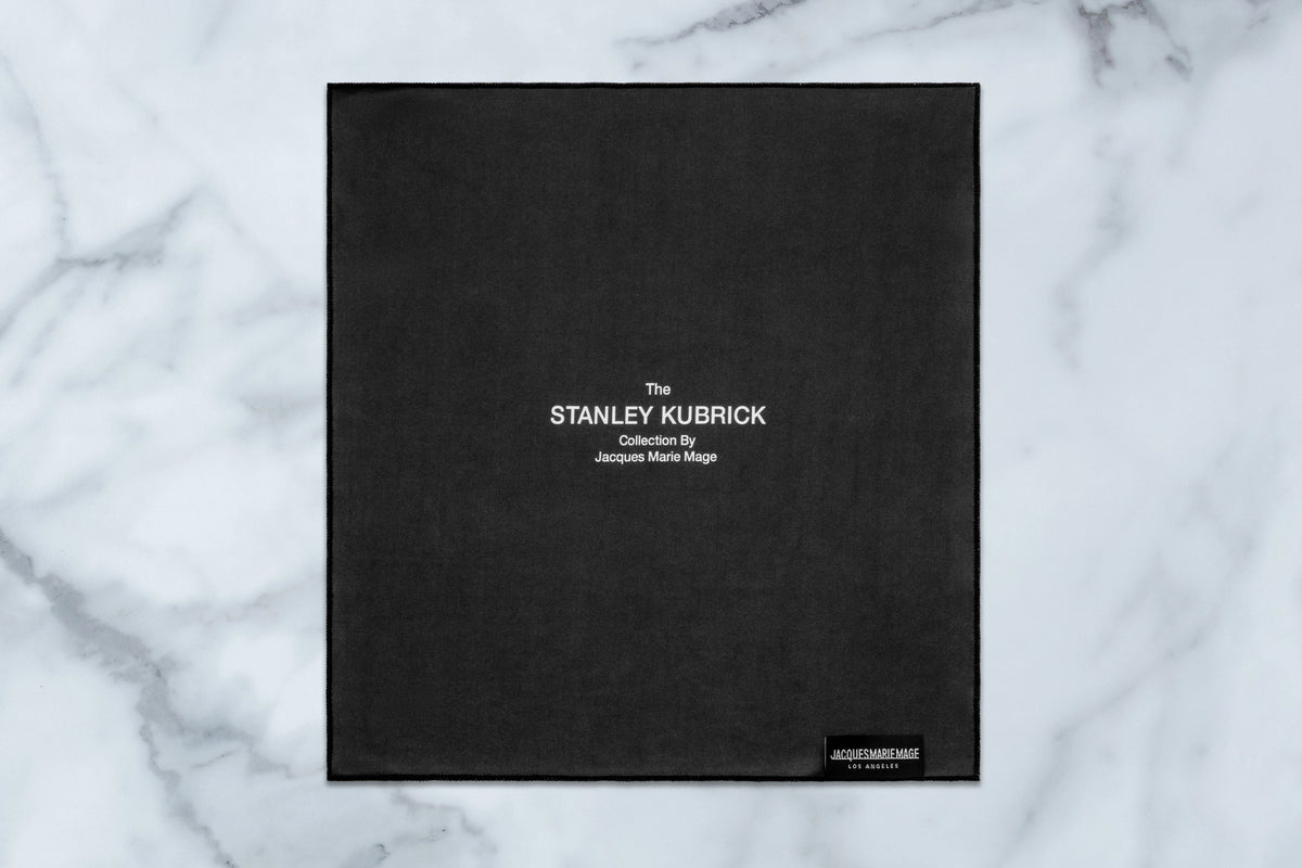 Black square microfiber cleaning cloth from the Stanley Kubrick by JMM: 1948 collection, featuring the text The STANLEY KUBRICK Collection By Jacques Marie Mage and a small branded logo tag in the corner.