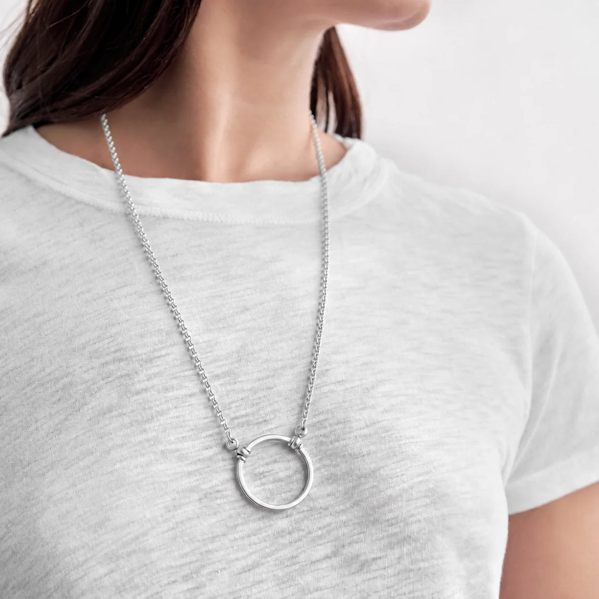 A silver La Loop Claudia necklace featuring a circular pendant loop worn around the neck as a lightweight glasses holder.