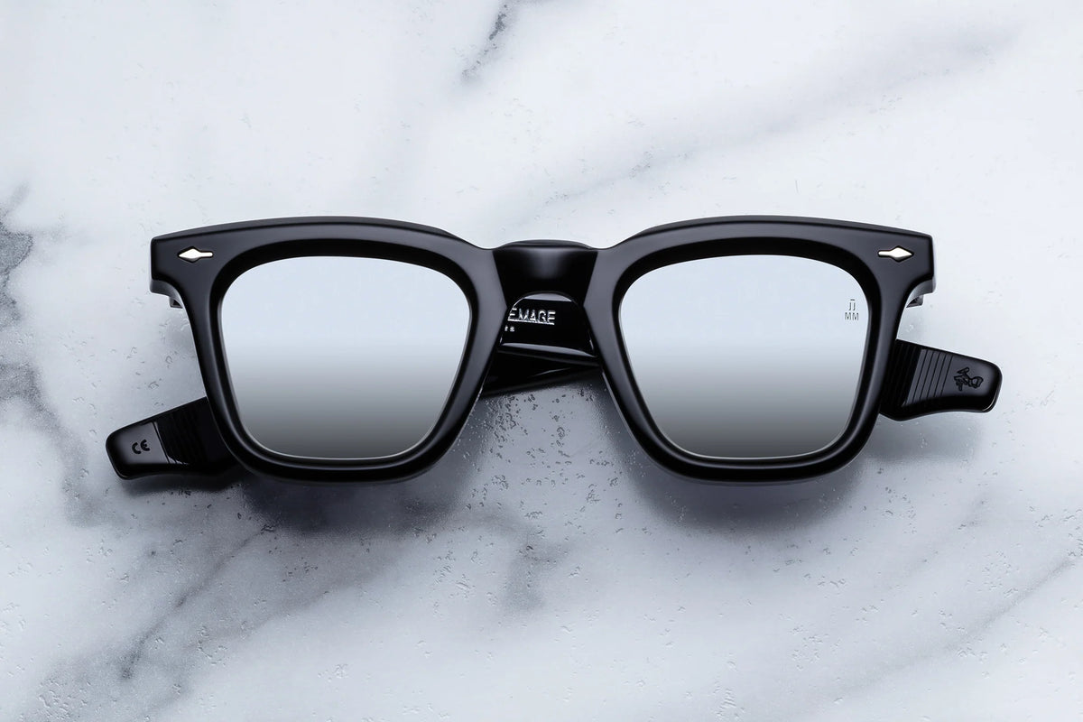 Black Wellington-shaped Jacques Marie Mage Leclair sunglasses with mirrored lenses resting on a white marble surface.