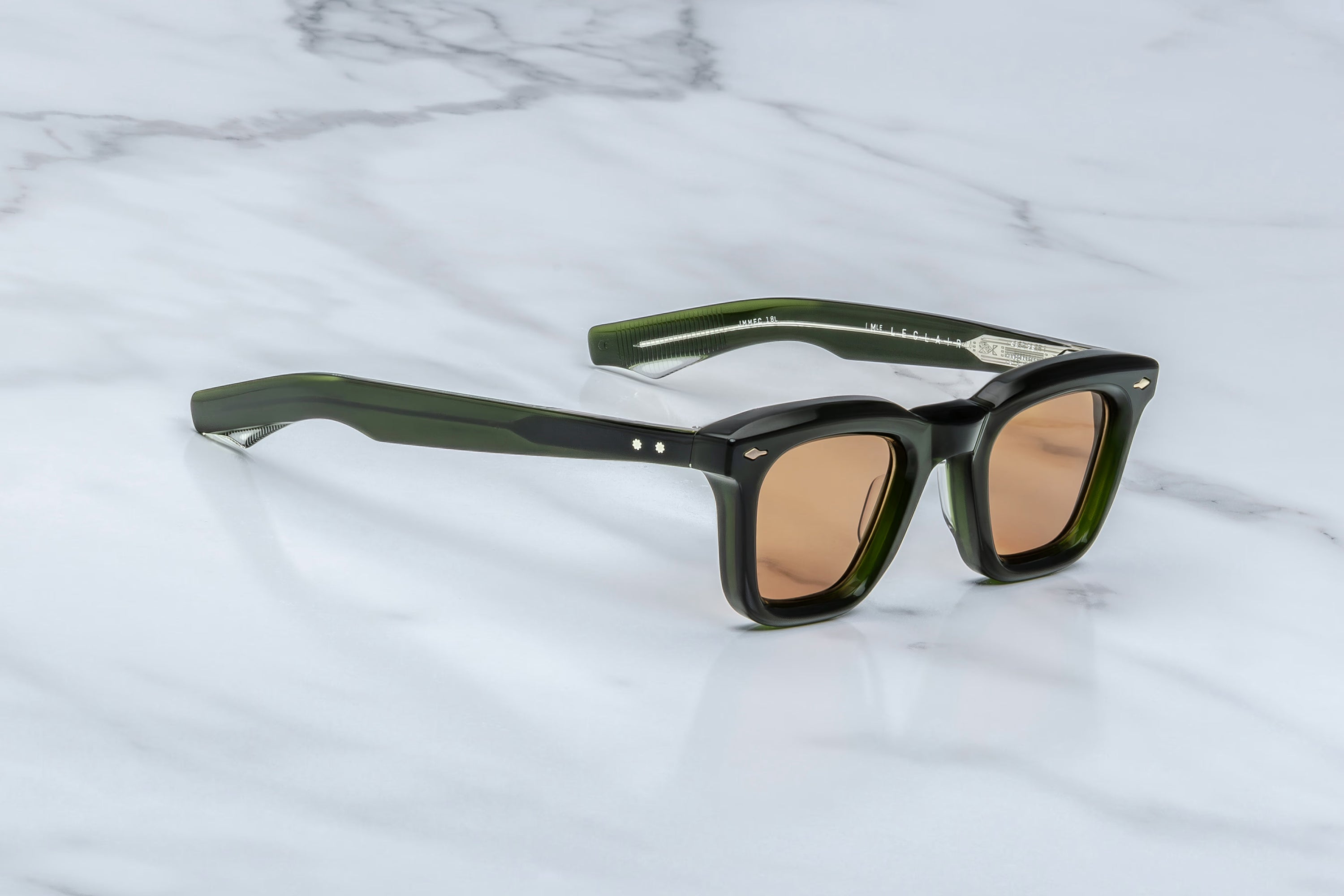 Sunglasses with green frames and brown lenses on a marble surface