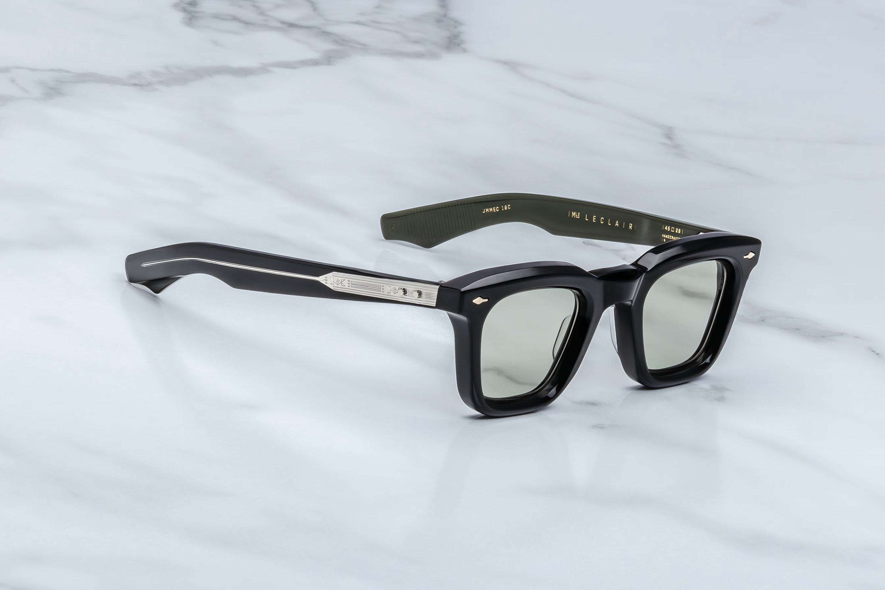 Black sunglasses with green accents on a marble surface