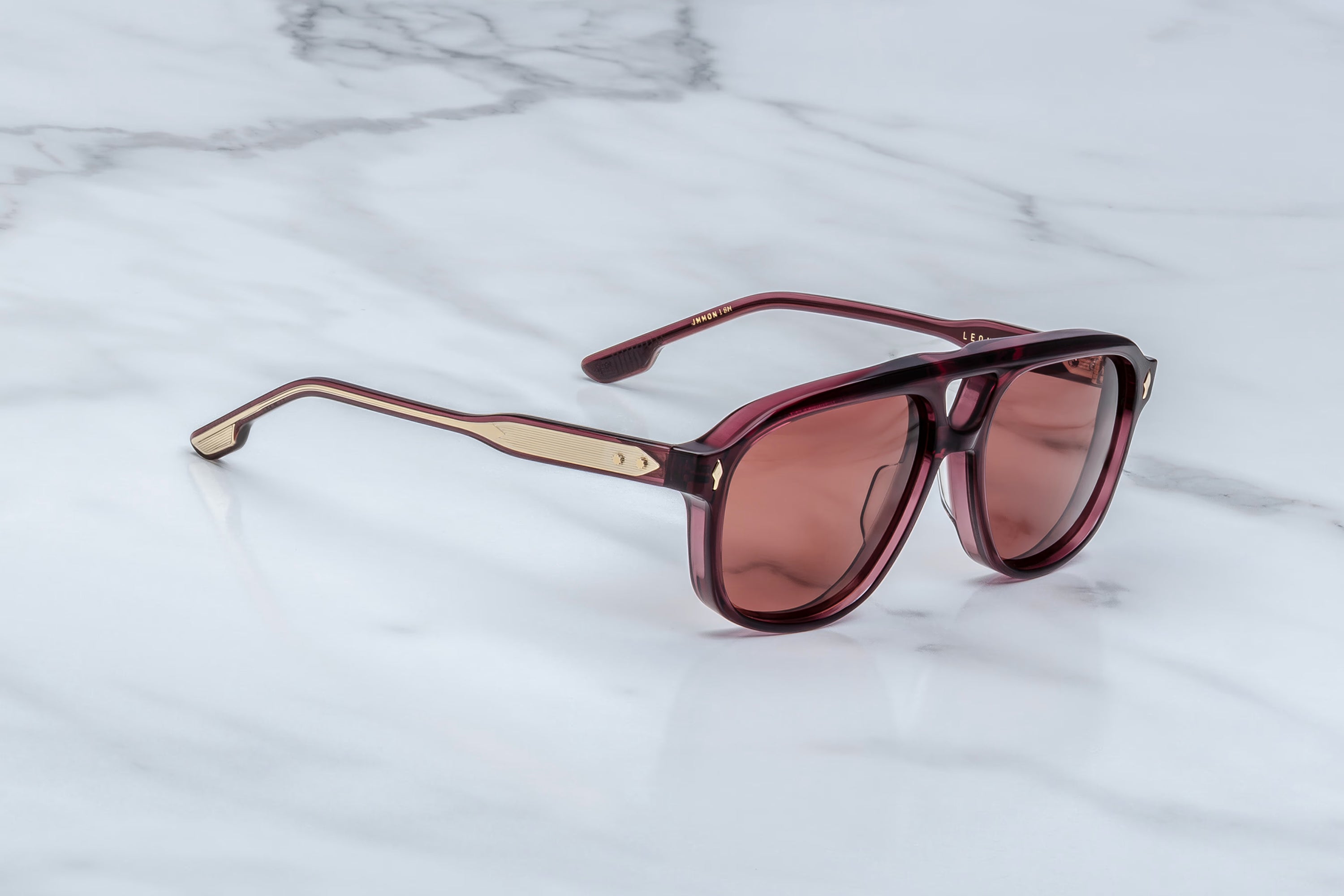 Sunglasses with a maroon tint on a marble surface