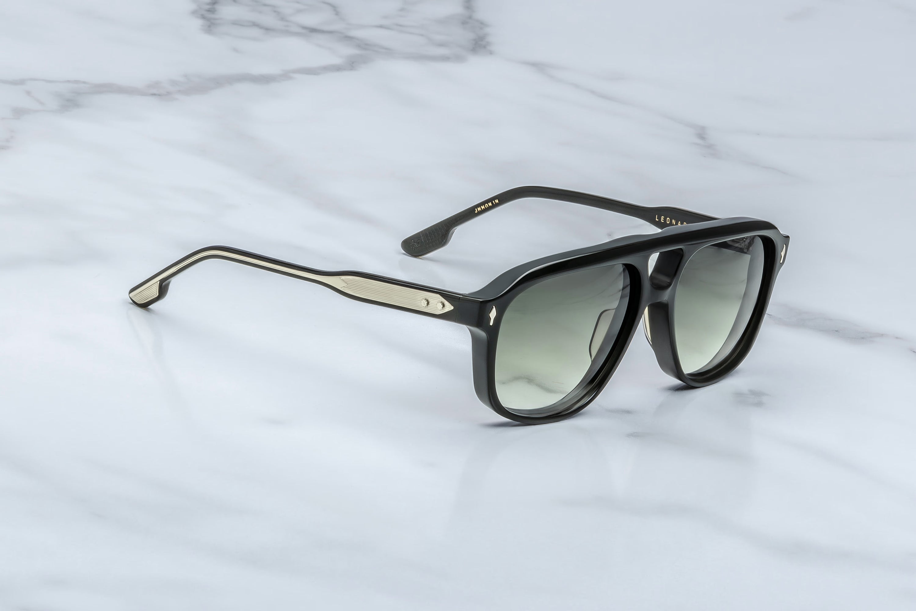 Sunglasses with gold and black frame on a marble surface