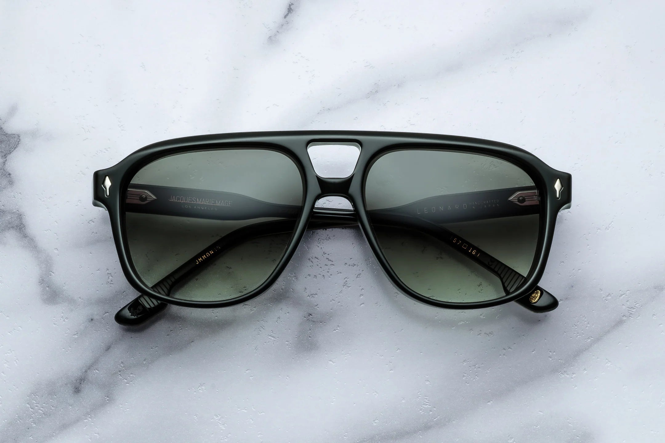 Black sunglasses with green lenses on a marble surface