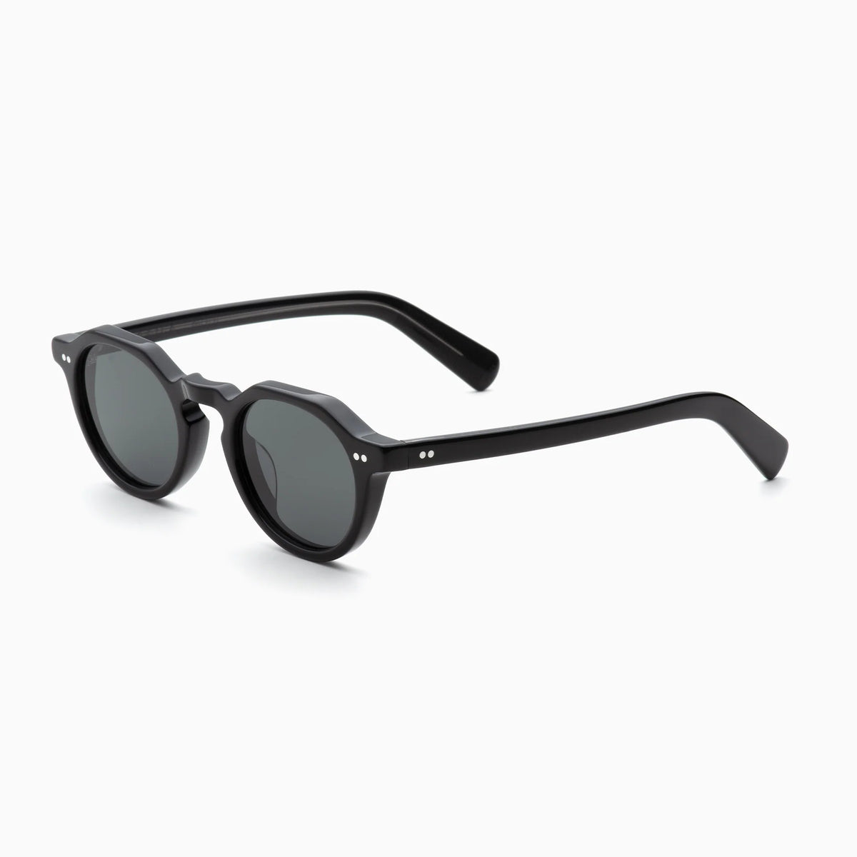 Akila Lola by Akila: Black round sunglasses with dark lenses, a thick contemporary frame, and subtle silver accents on the front corners, featuring paddle-shaped temples for added style, shown on a white background at a slight angle.
