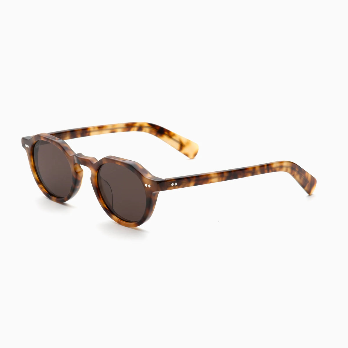 The Akila Lola sunglasses by Akila feature brown tortoiseshell frames with round dark lenses and thick, contemporary eyeglass frames. The design includes paddle-shaped temples, and the sunglasses are displayed on a white background, angled slightly to the right.