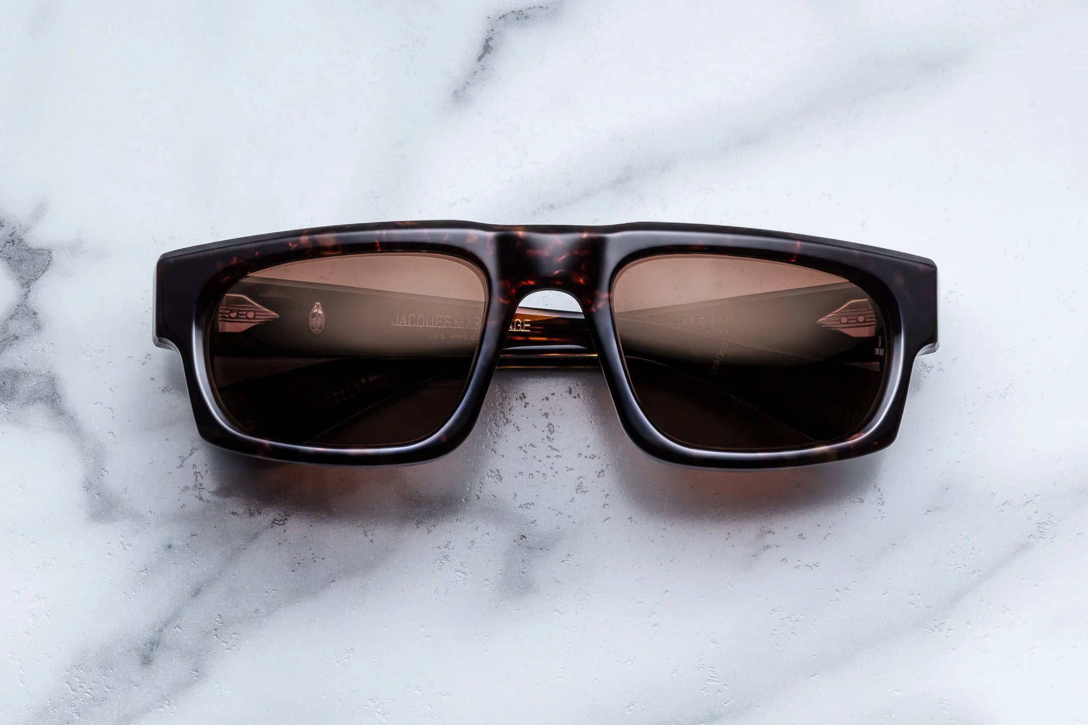 Sunglasses with tortoiseshell frame and dark lenses on a marble surface