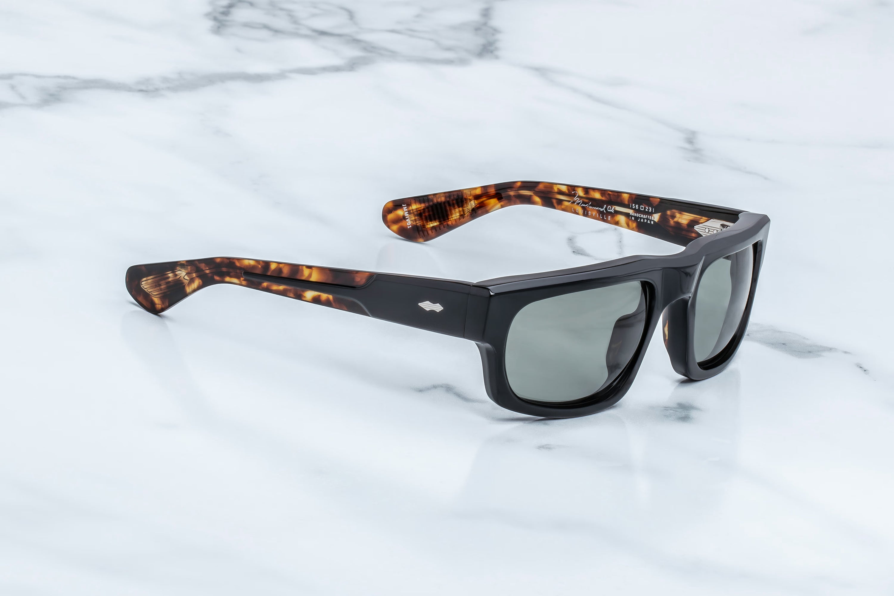 Sunglasses with tortoiseshell frame and black lenses on a light gray background