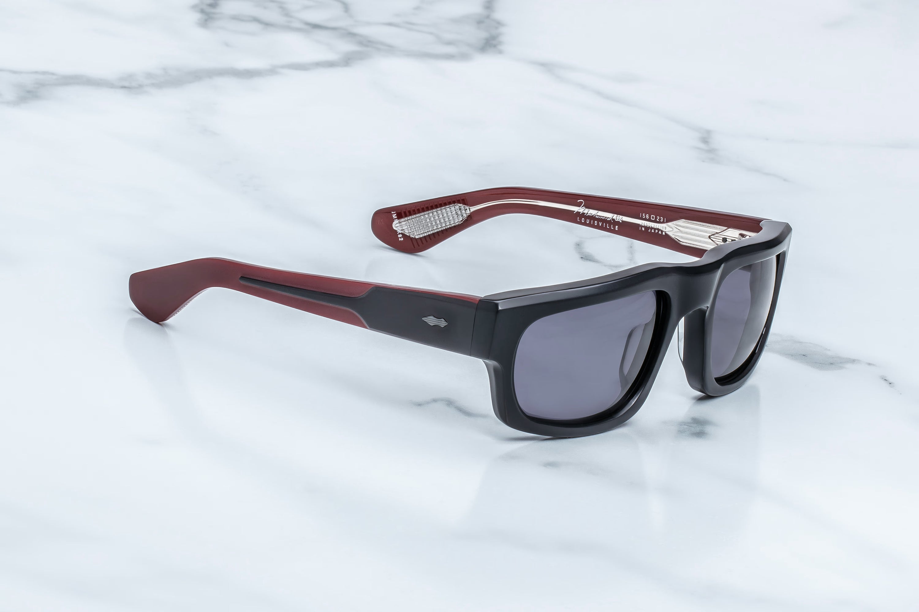 Sunglasses with red and black frame on a marble surface