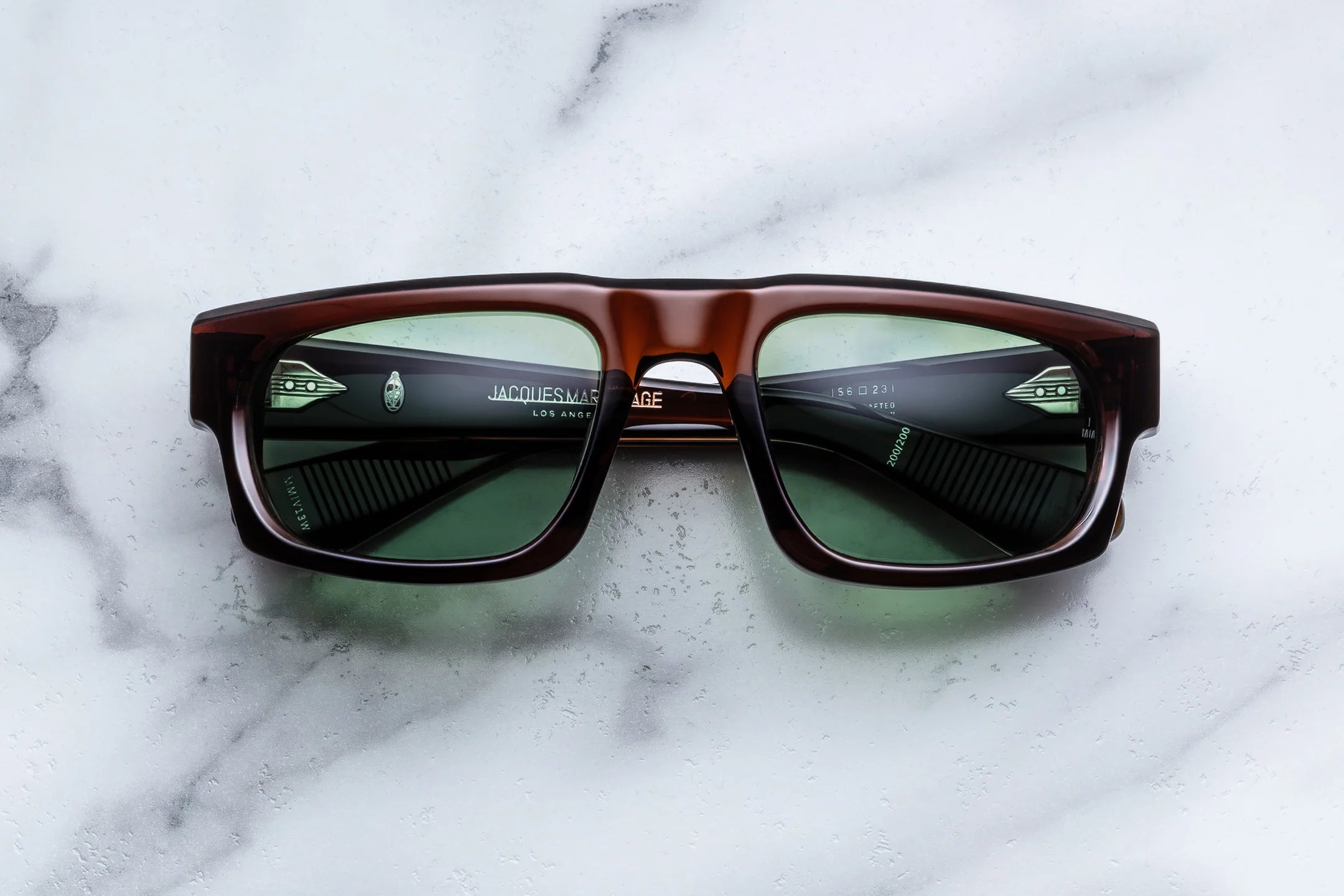 Sunglasses with brown frame and green lenses on a marble surface