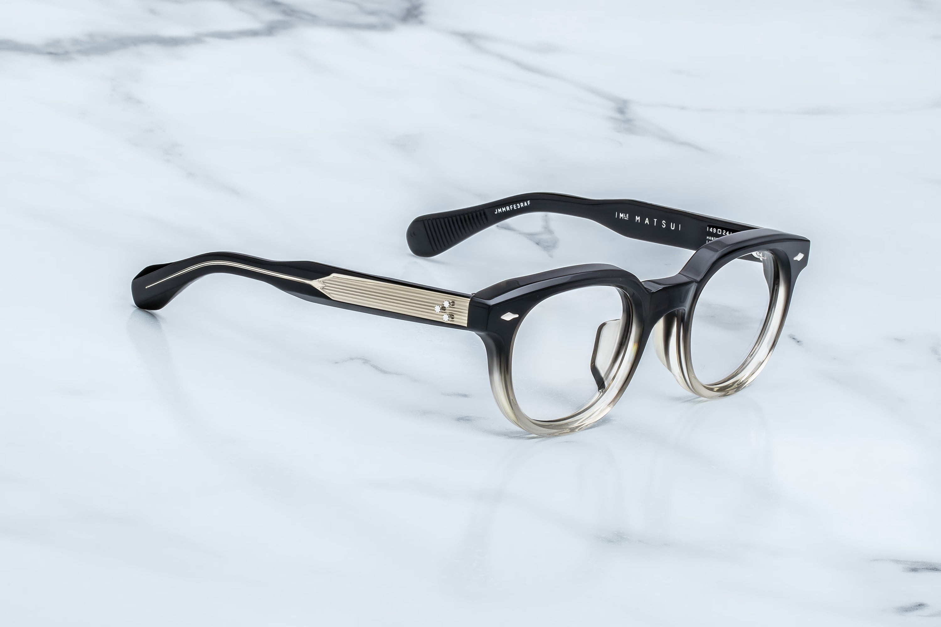 Black and gold eyeglasses on a light marble background