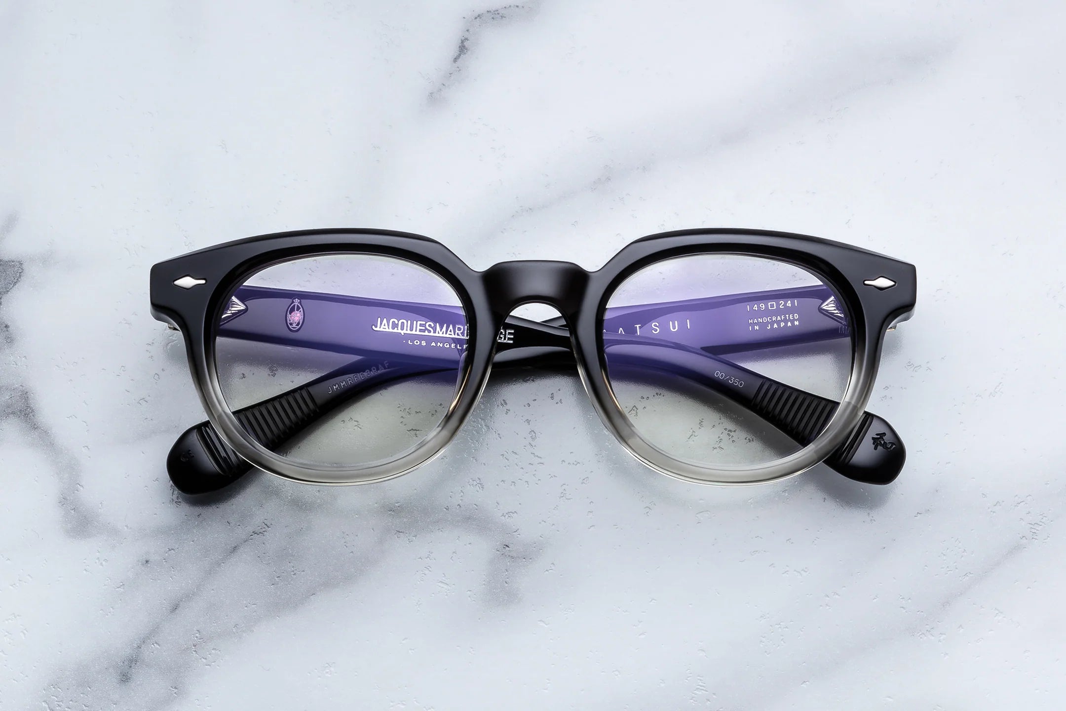 Round eyeglasses with black frame and purple lenses on a marble surface