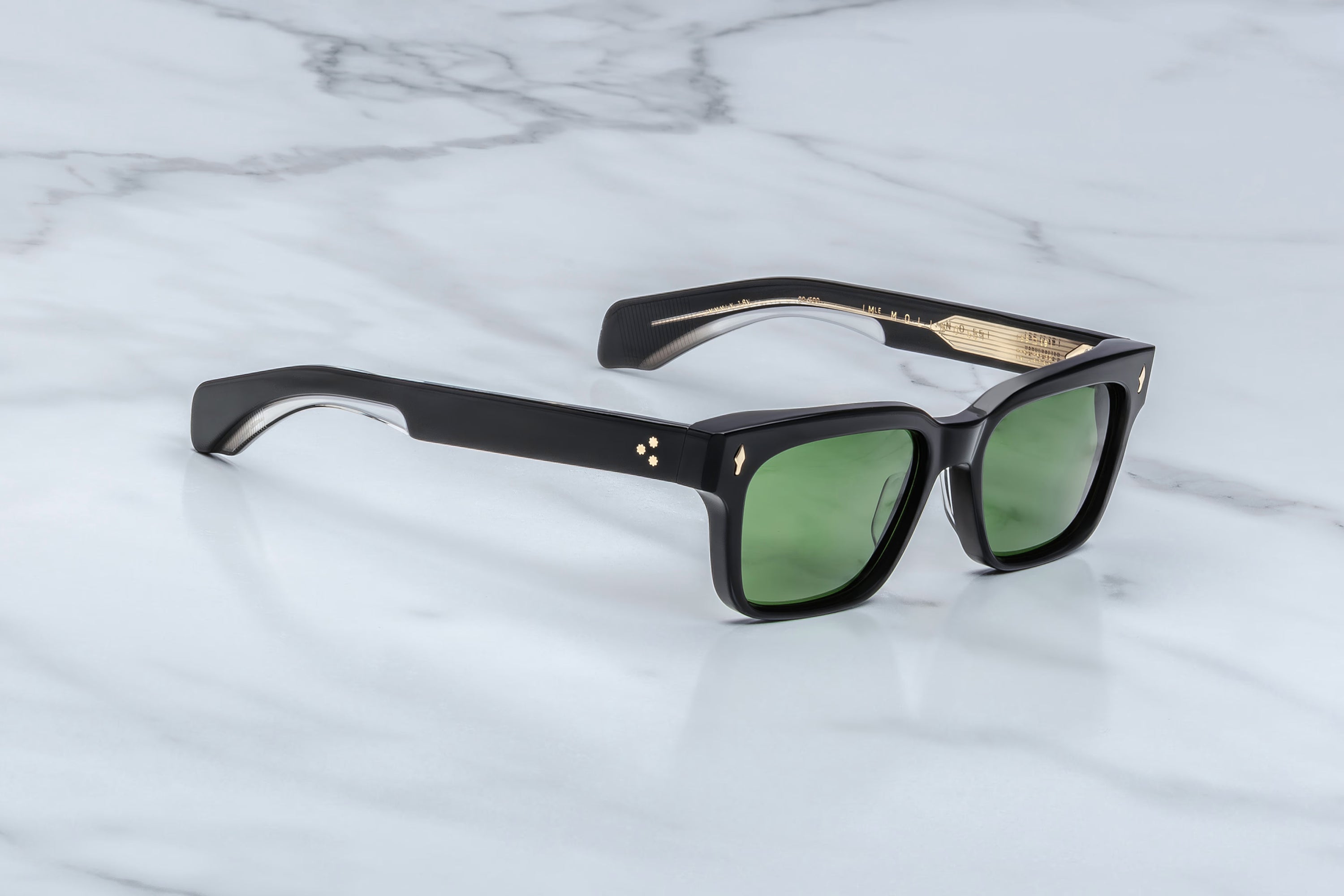 Black sunglasses with green lenses on a marble surface