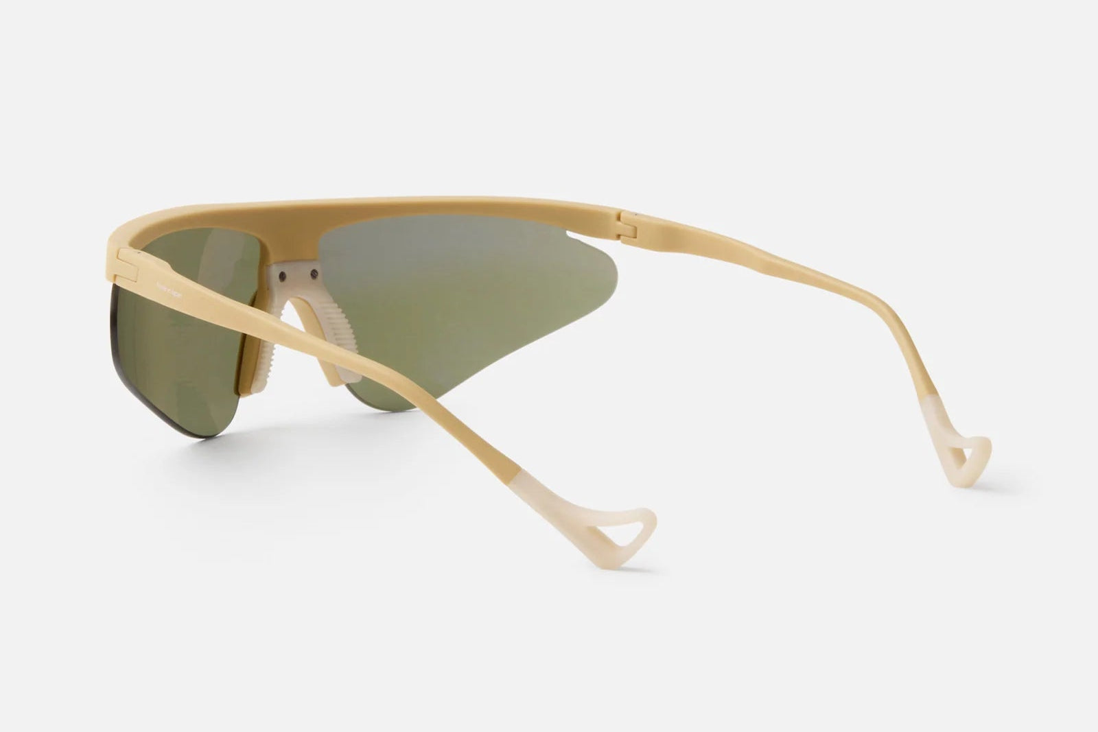 District Vision Momoka Pacer sunglasses by District Vision, featuring an ergonomic beige frame with wide arms and green-tinted shield-style lenses, are shown from a rear-side angle against a plain white background.
