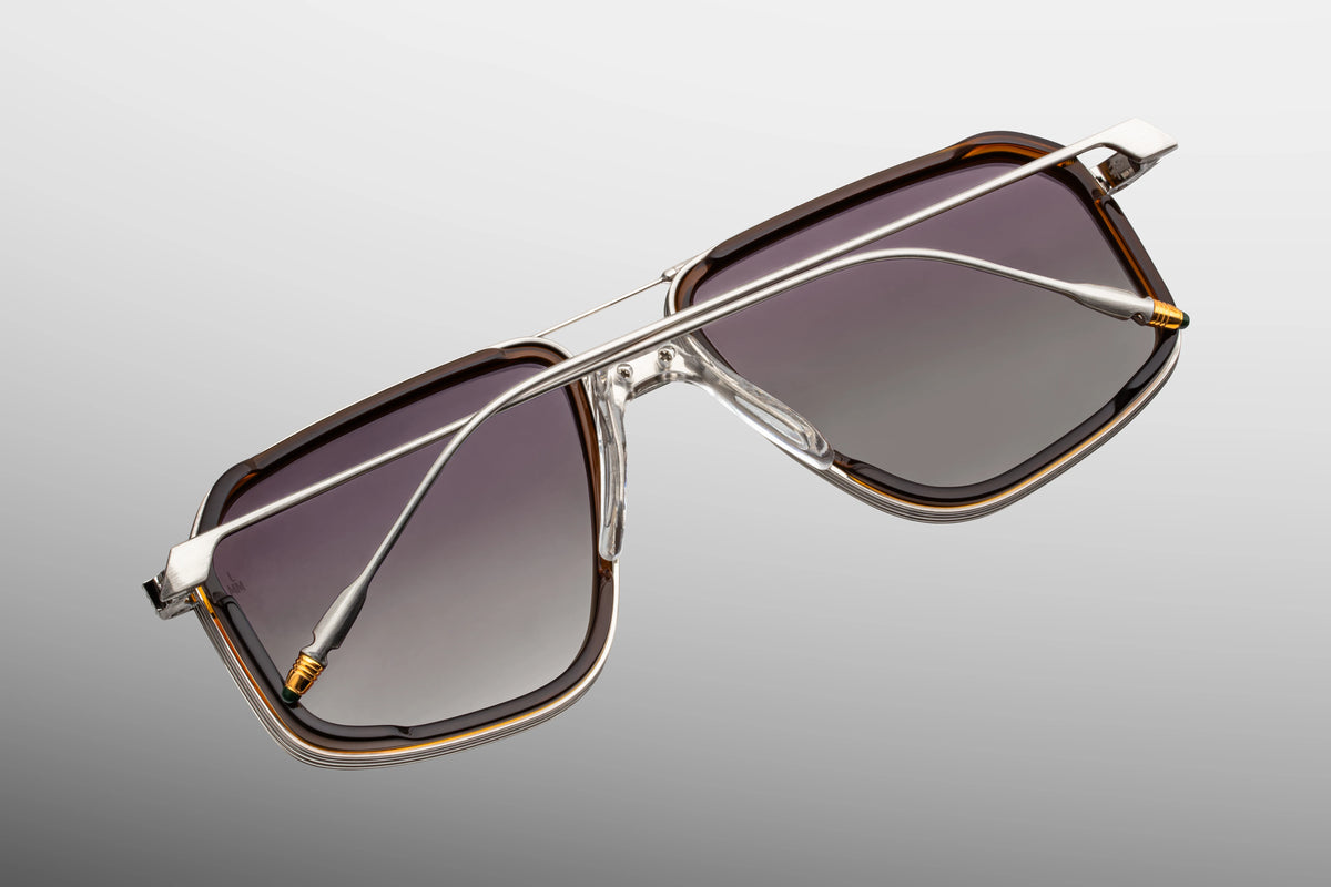 Jacques Marie Mage Yellowstone VII: Moran In Mammoth navigator sunglasses with silver beta titanium frames, gold-tone accents, and dark gradient lenses set in brown rims.
