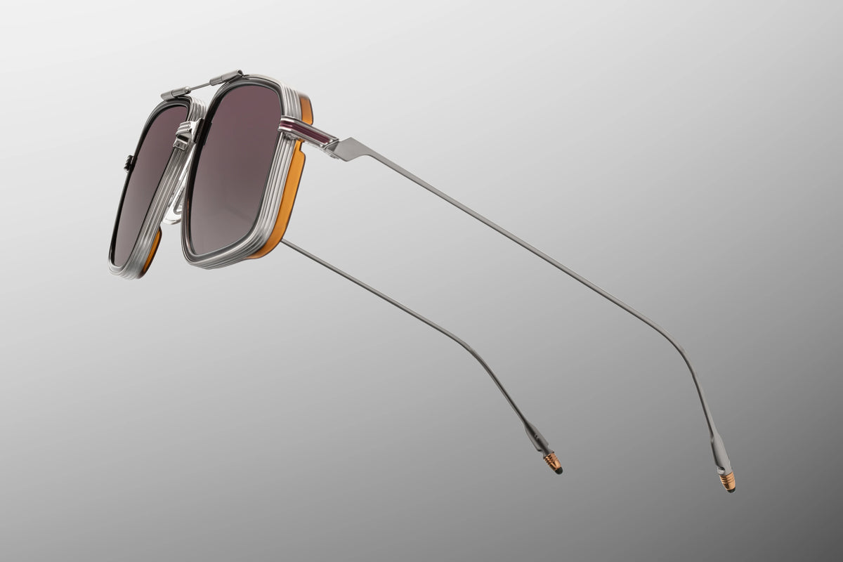 Jacques Marie Mage Yellowstone VII: Moran In Mammoth angular beta titanium sunglasses with silver metal frames, thick orange rims, and gradient lenses.
