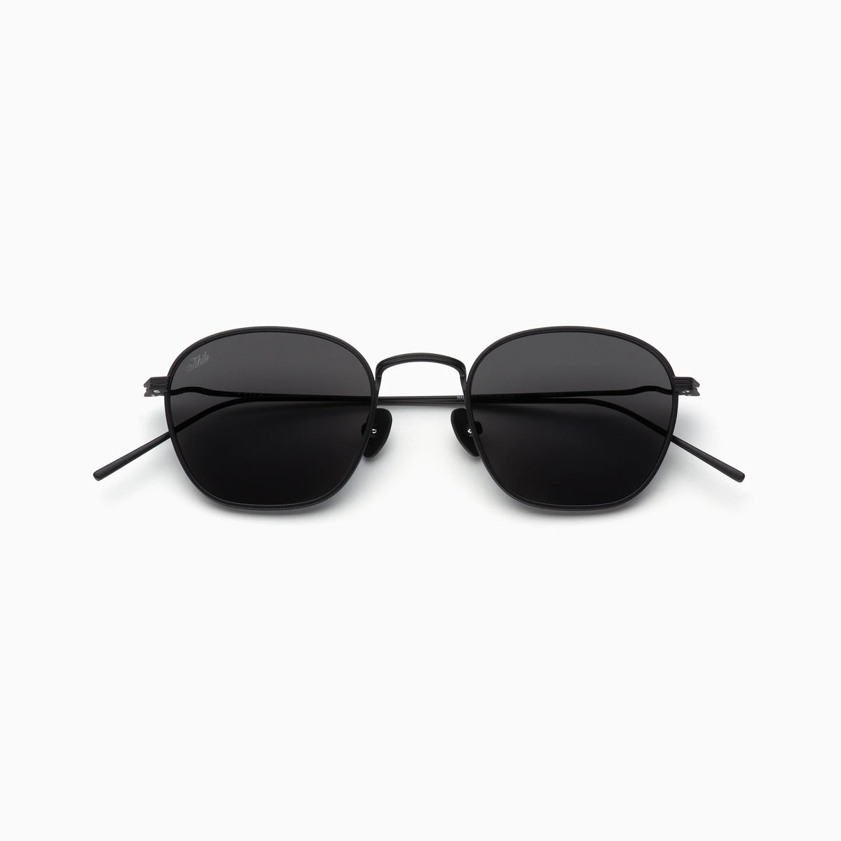 Akila Osiris sunglasses from the Akila Titanium Collection, featuring black round-square frames with thin, lightweight metal construction and dark tinted lenses, displayed on a white background and viewed from the front.