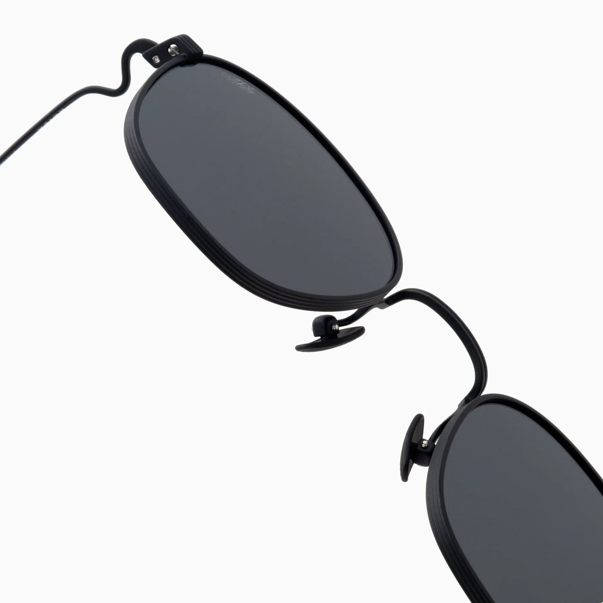 Close-up of the Akila Osiris black oval sunglasses with dark lenses, highlighting the thin titanium eyeglass frames and nose pads against a plain white background. Part of the Akila Titanium Collection, these lightweight metal sunglasses combine style with comfort.