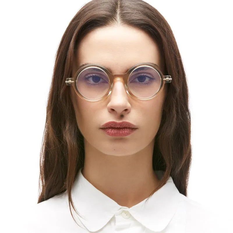 A person wearing thick, round, translucent beige Kuboraum P1 mask glasses handmade in Italy.