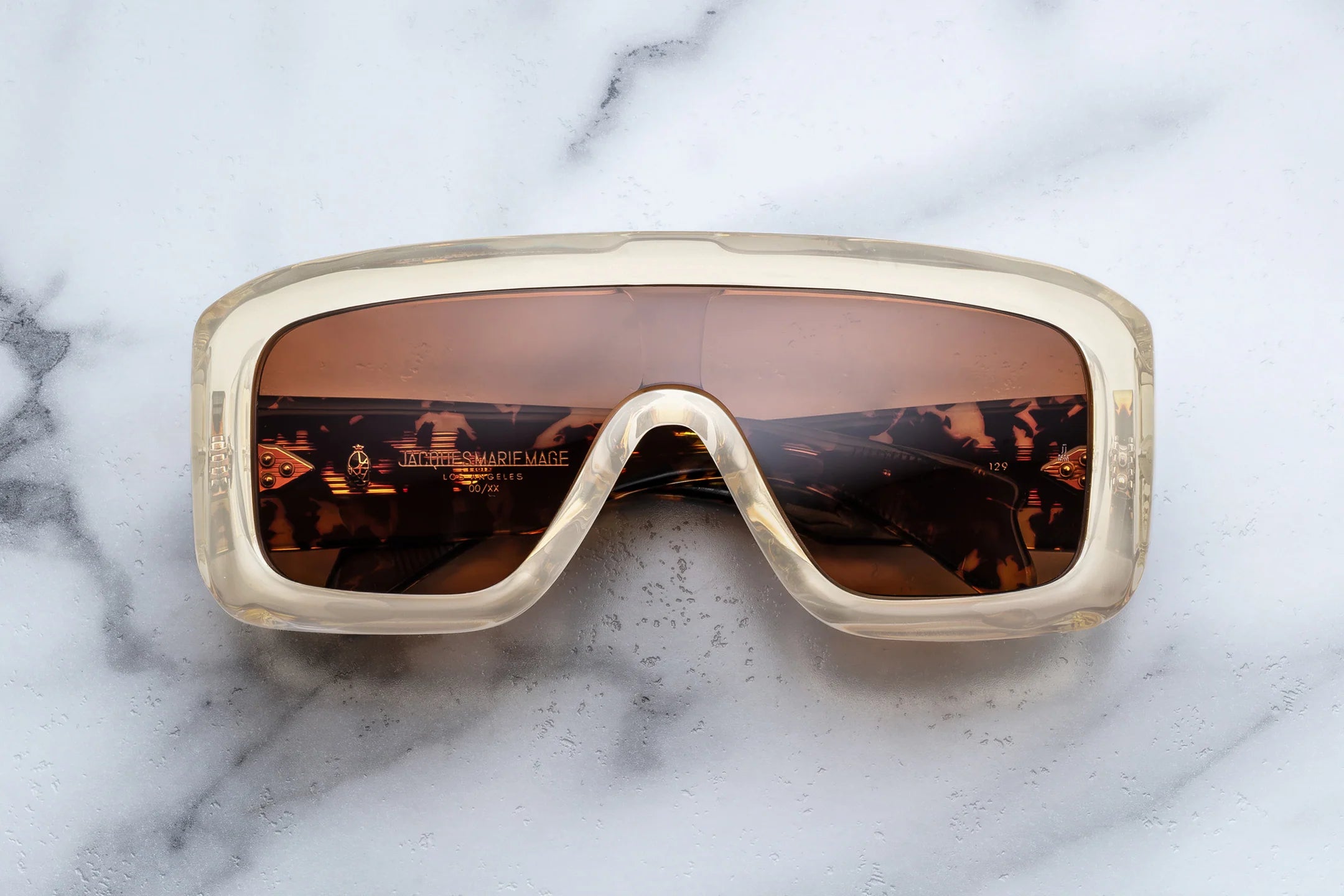 Sunglasses with a gold frame and brown lenses on a marble surface
