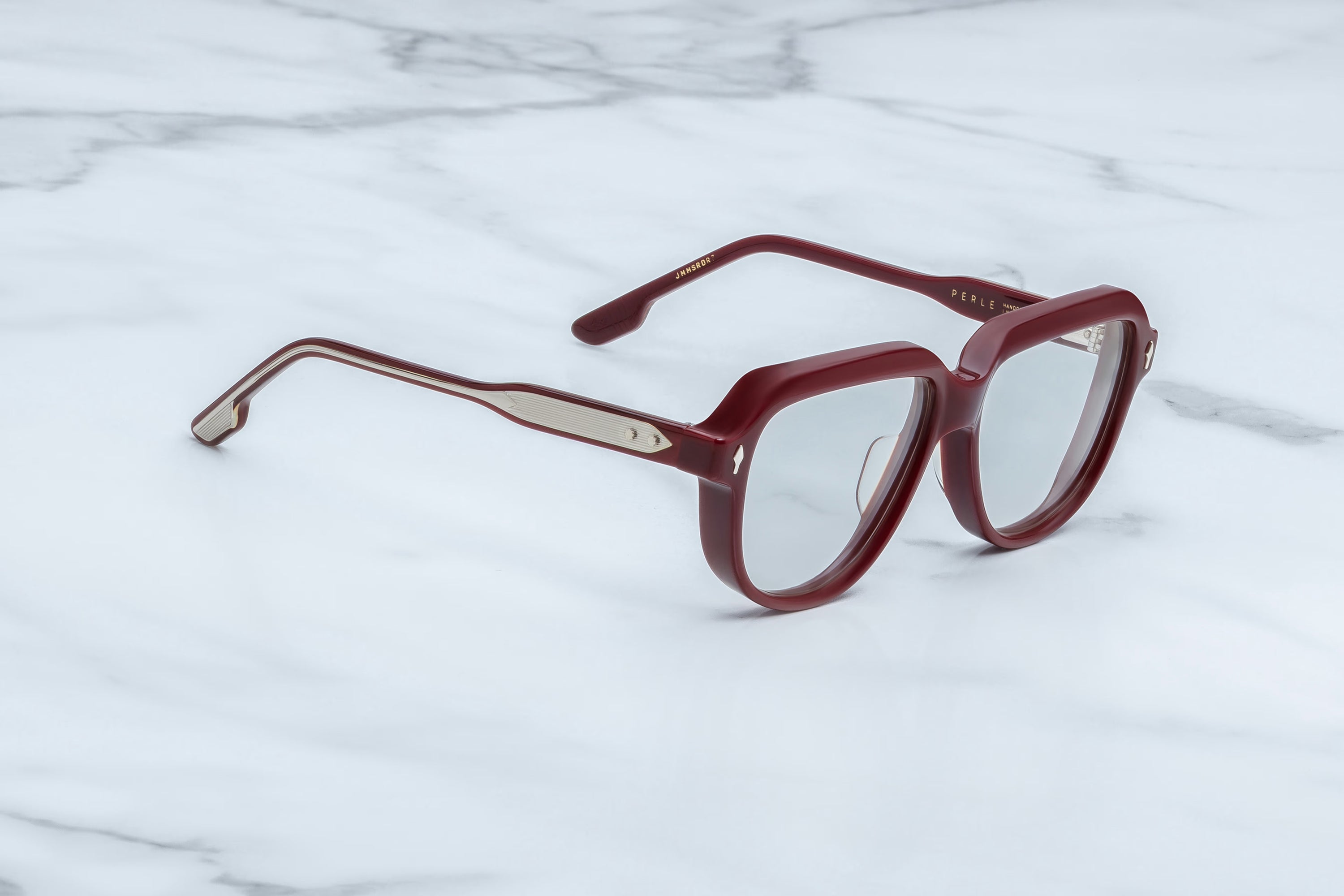 Red eyeglasses on a white marble surface