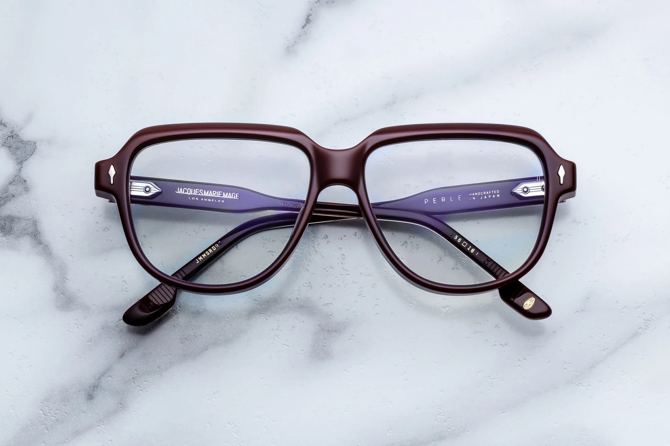 Pair of eyeglasses with a maroon frame on a marble surface