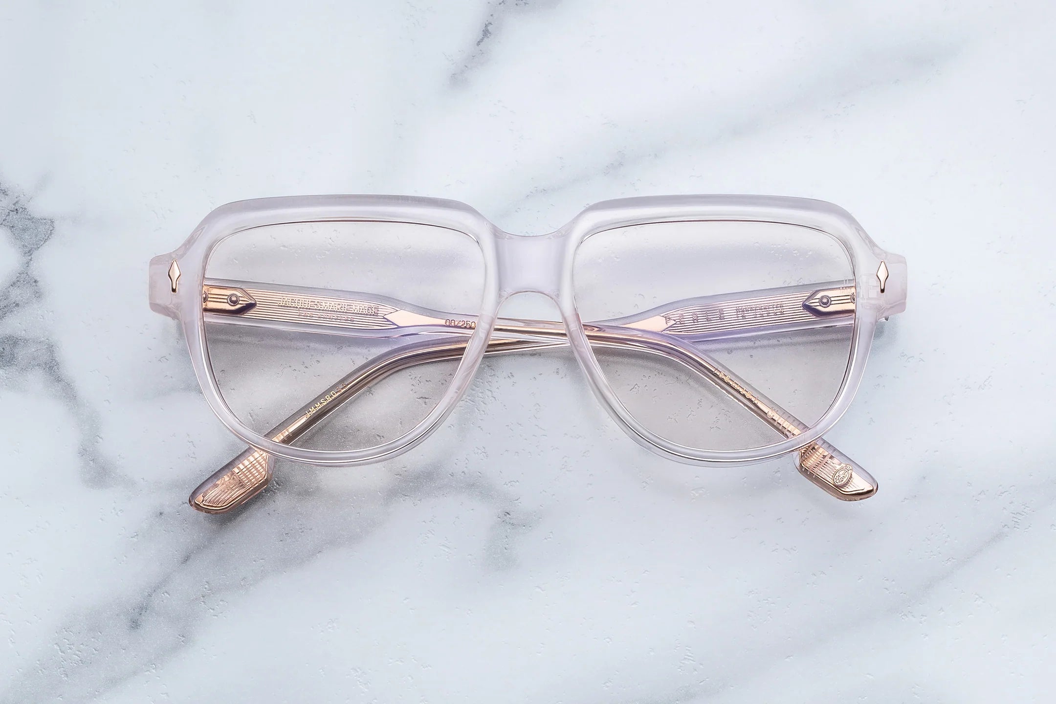Clear eyeglasses with gold accents on a marble surface