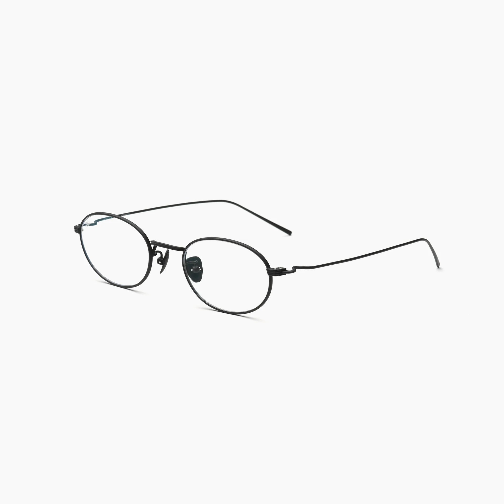 Black oval optical glasses with thin metal rims, clear lenses, adjustable nose pads, and slim wire temples, shown at an angled side view on a white background.