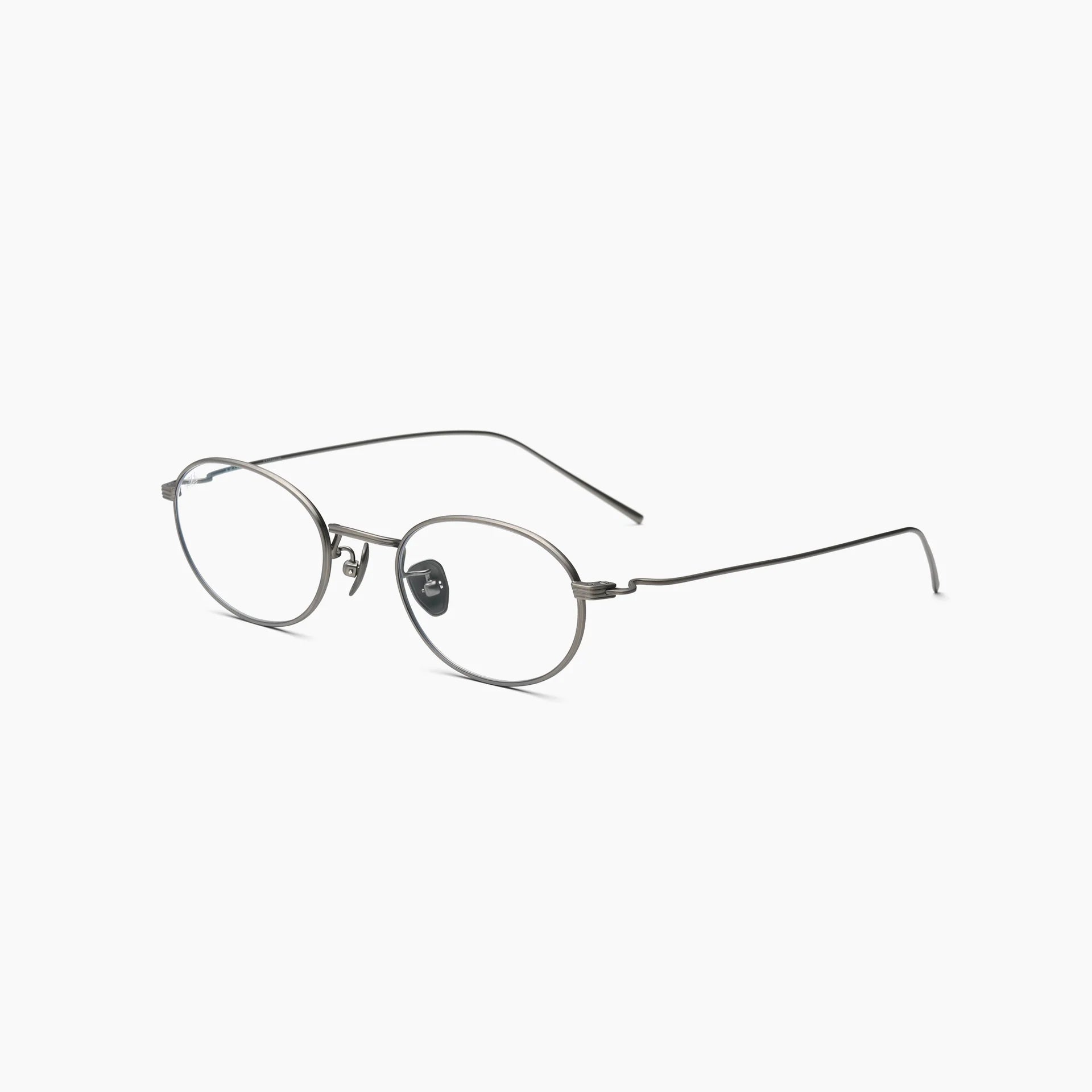 Silver oval optical glasses with thin metal rims, clear lenses, adjustable nose pads, and slim wire temples, shown at an angled side view on a white background.