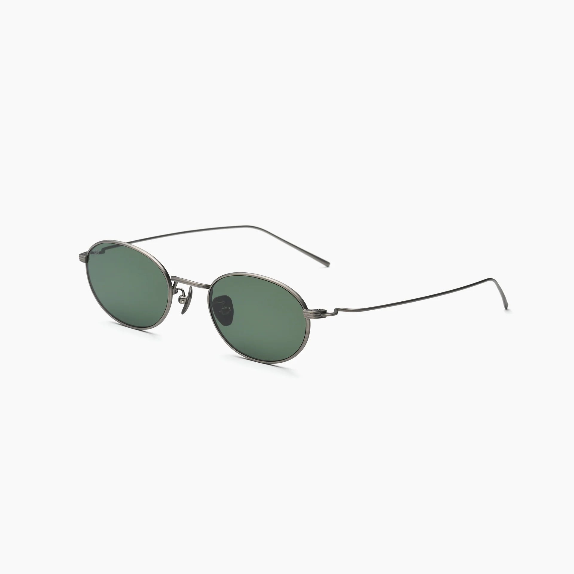 Oval metal-frame sunglasses with green lenses, adjustable nose pads, and slim wire temples, shown at an angled side view on a white background.